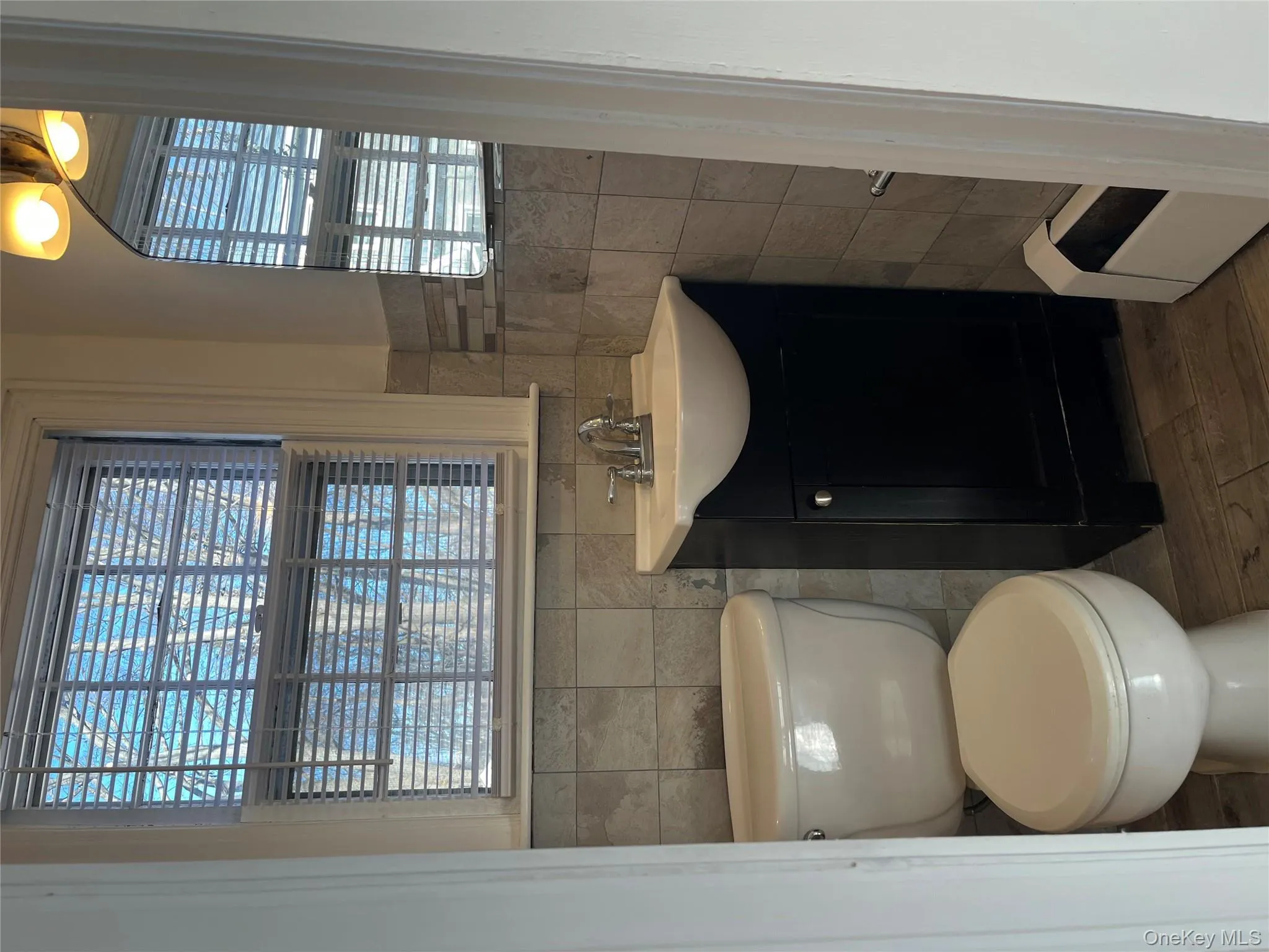 Half bathroom featuring vanity, plenty of natural light, a baseboard heating unit, tile walls, and dark wood-style floors Half bathroom featuring vanity, plenty of natural light, a baseboard heating unit, tile walls, and dark wood-style floors