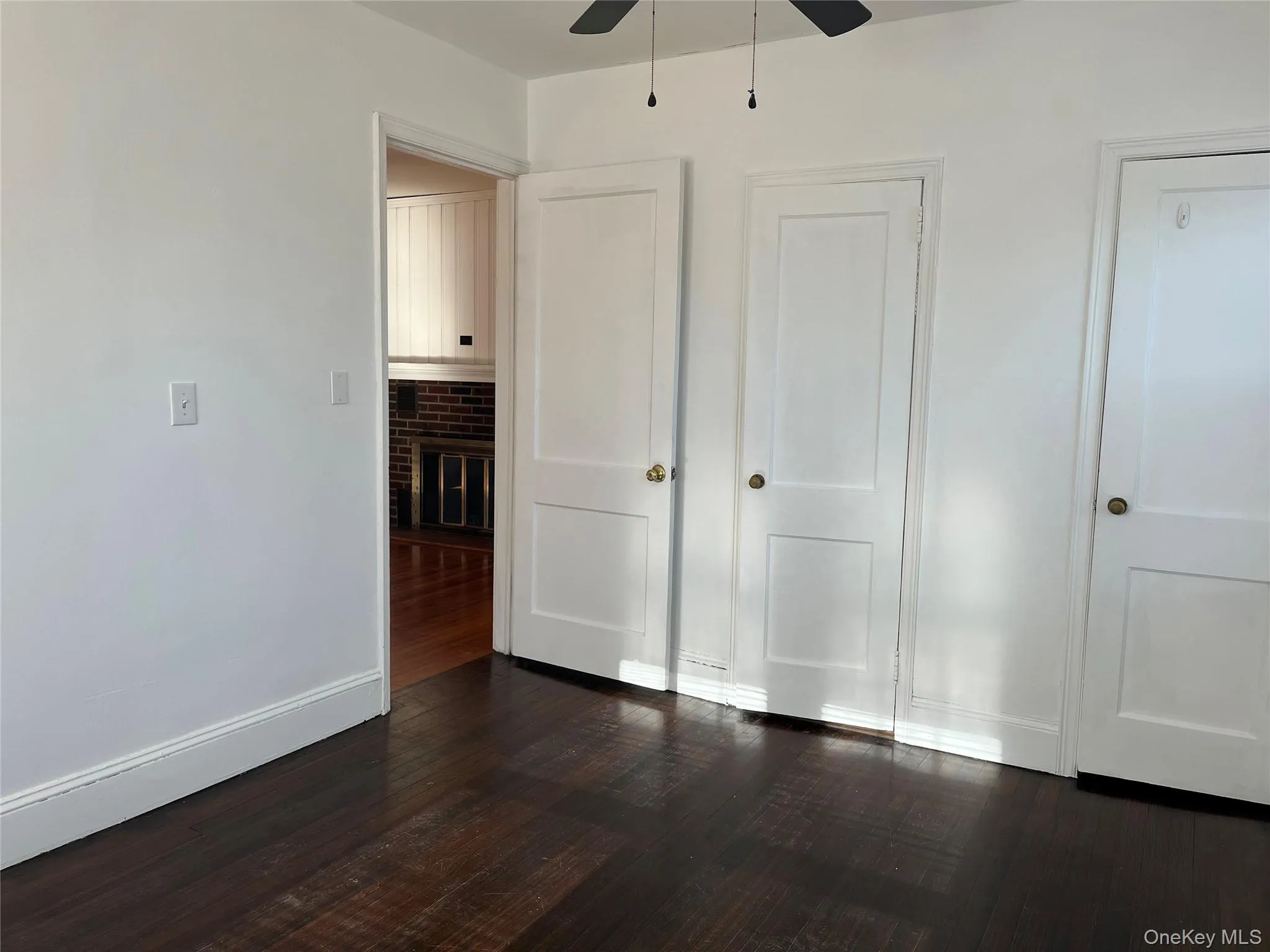 Unfurnished bedroom with multiple closets, dark wood finished floors, and a ceiling fan Unfurnished bedroom with multiple closets, dark wood finished floors, and a ceiling fan