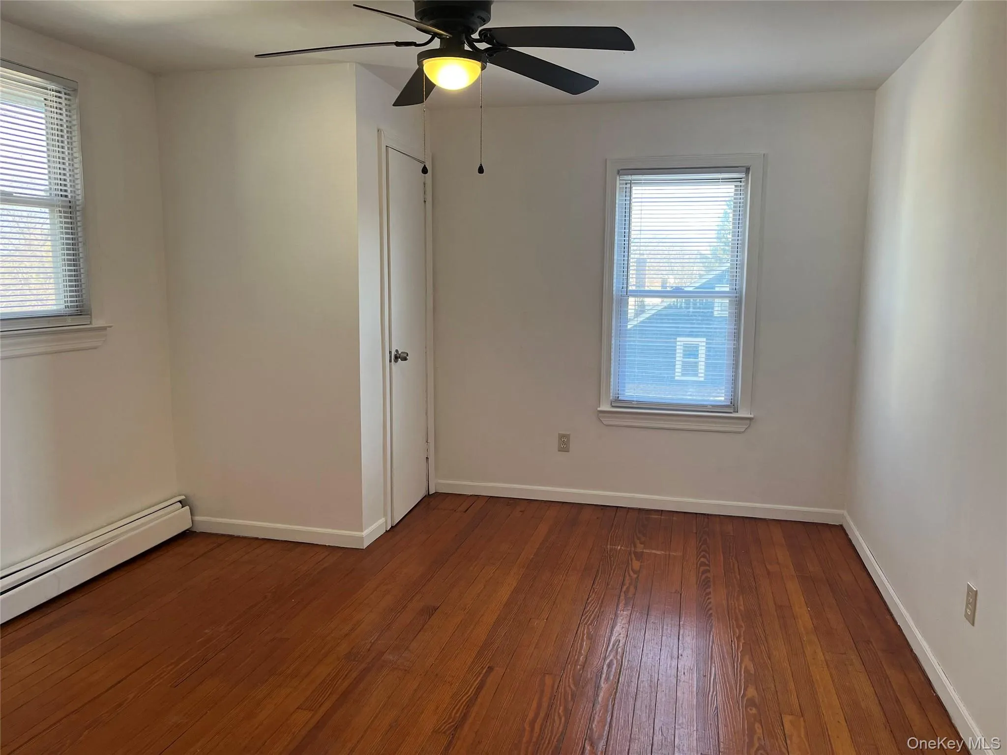 Empty room with dark wood-style flooring and ceiling fan Empty room with dark wood-style flooring and ceiling fan