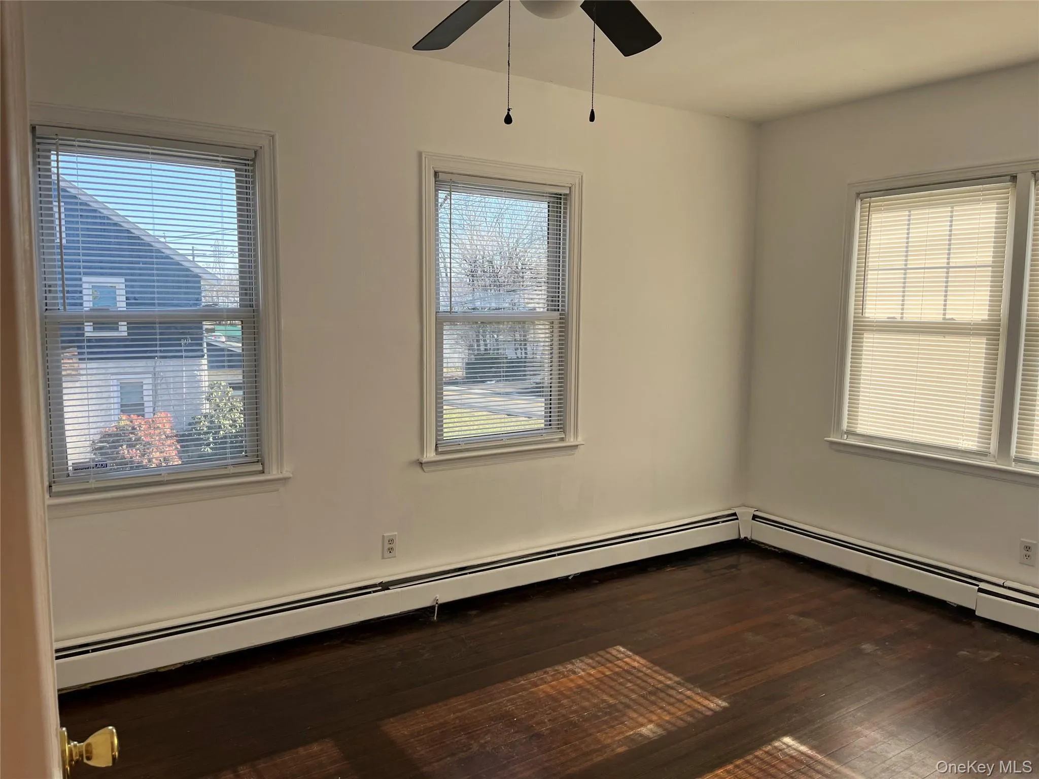 Spare room with dark wood finished floors, baseboard heating, and healthy amount of natural light Spare room with dark wood finished floors, baseboard heating, and healthy amount of natural light