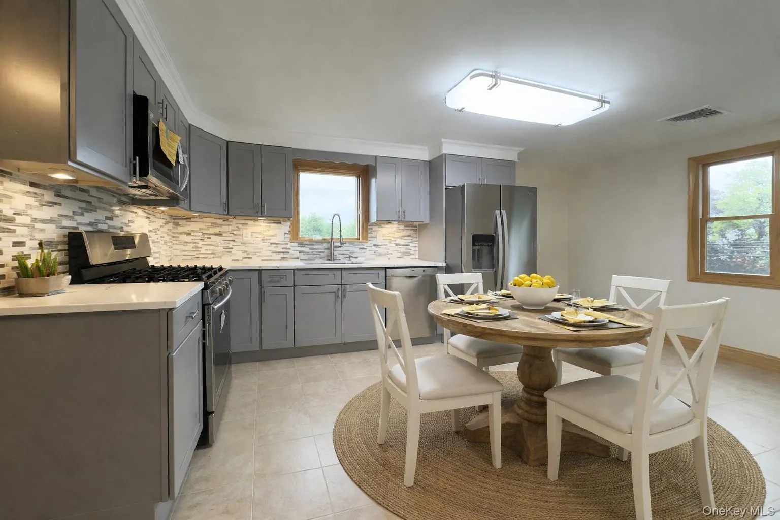 Kitchen with stainless steel appliances, gray cabinets, backsplash, and light tile patterned flooring Kitchen with stainless steel appliances, gray cabinets, backsplash, and light tile patterned flooring