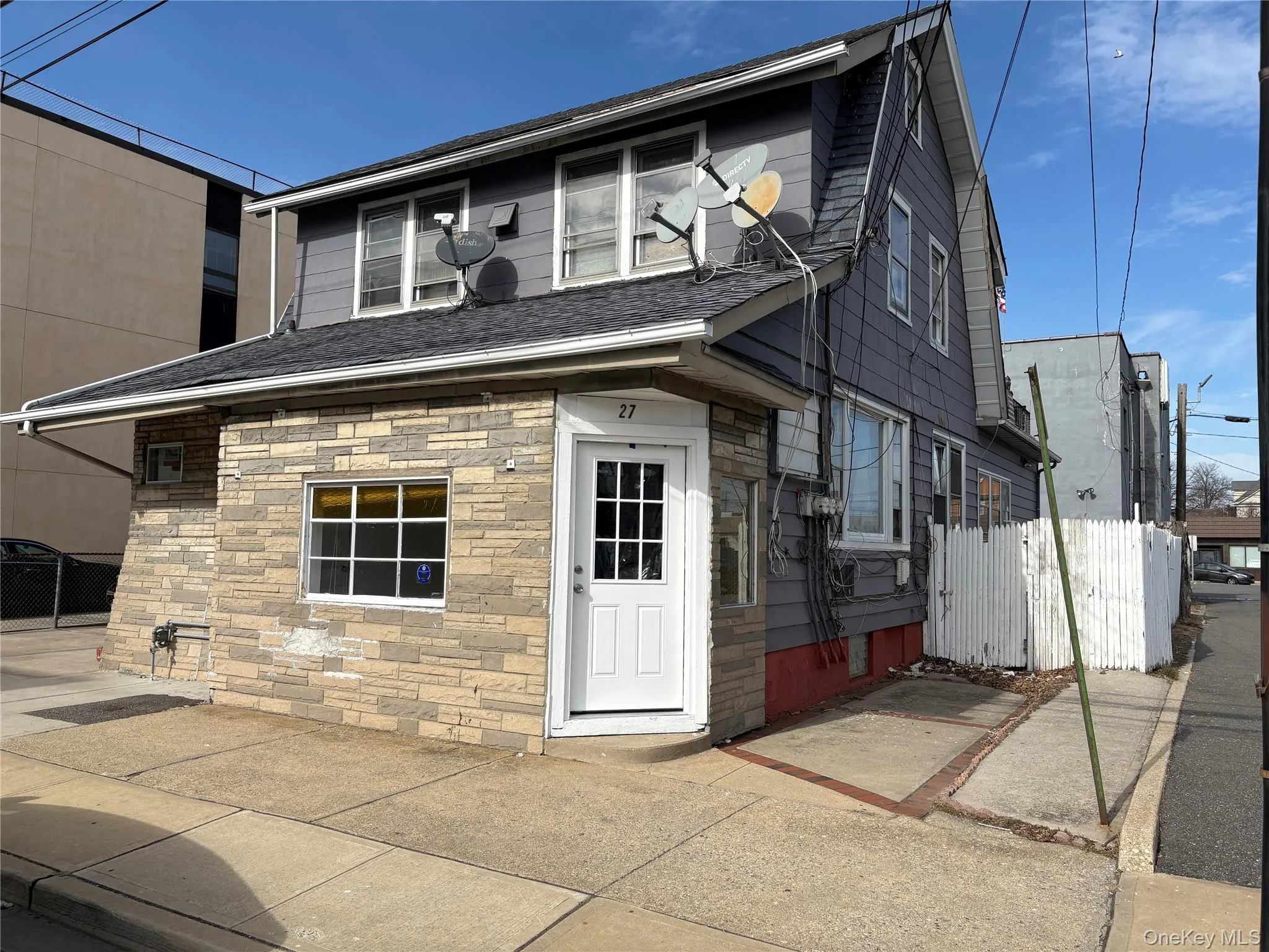 Back of property featuring stone siding and a shingled roof Back of property featuring stone siding and a shingled roof