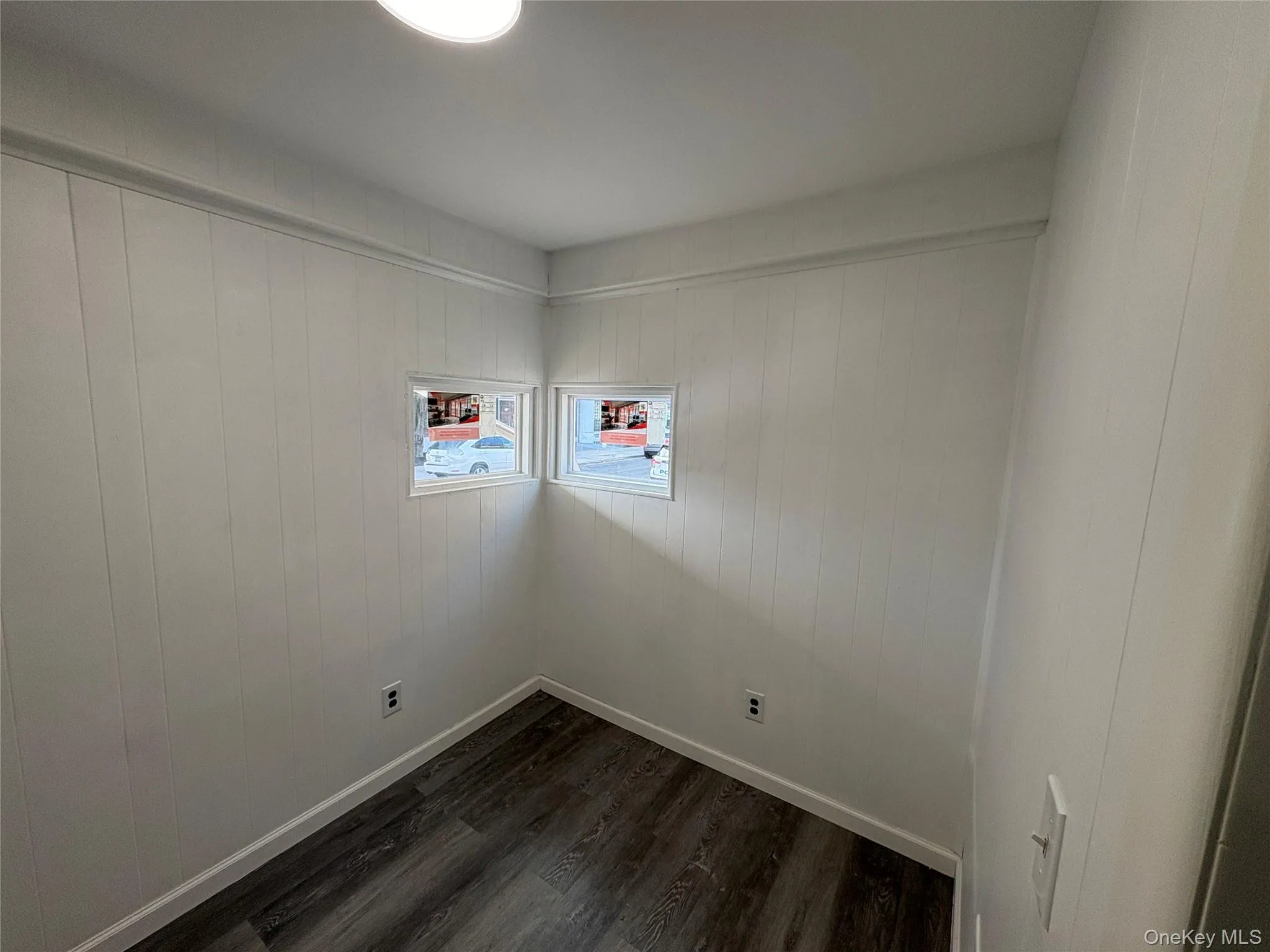 Unfurnished room featuring dark wood-style flooring and baseboards Unfurnished room featuring dark wood-style flooring and baseboards