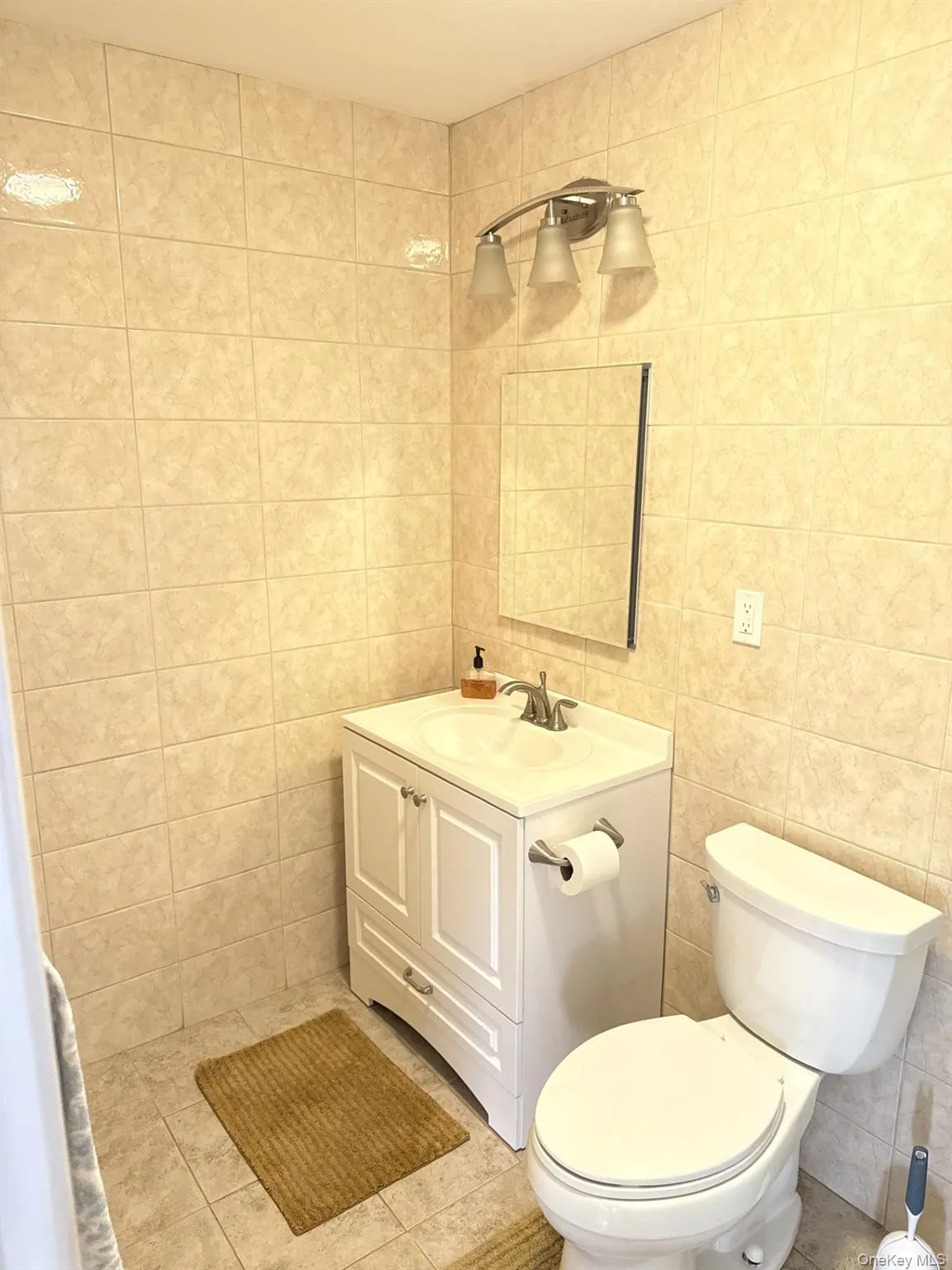 Bathroom featuring vanity, tile walls, and light tile patterned floors Bathroom featuring vanity, tile walls, and light tile patterned floors