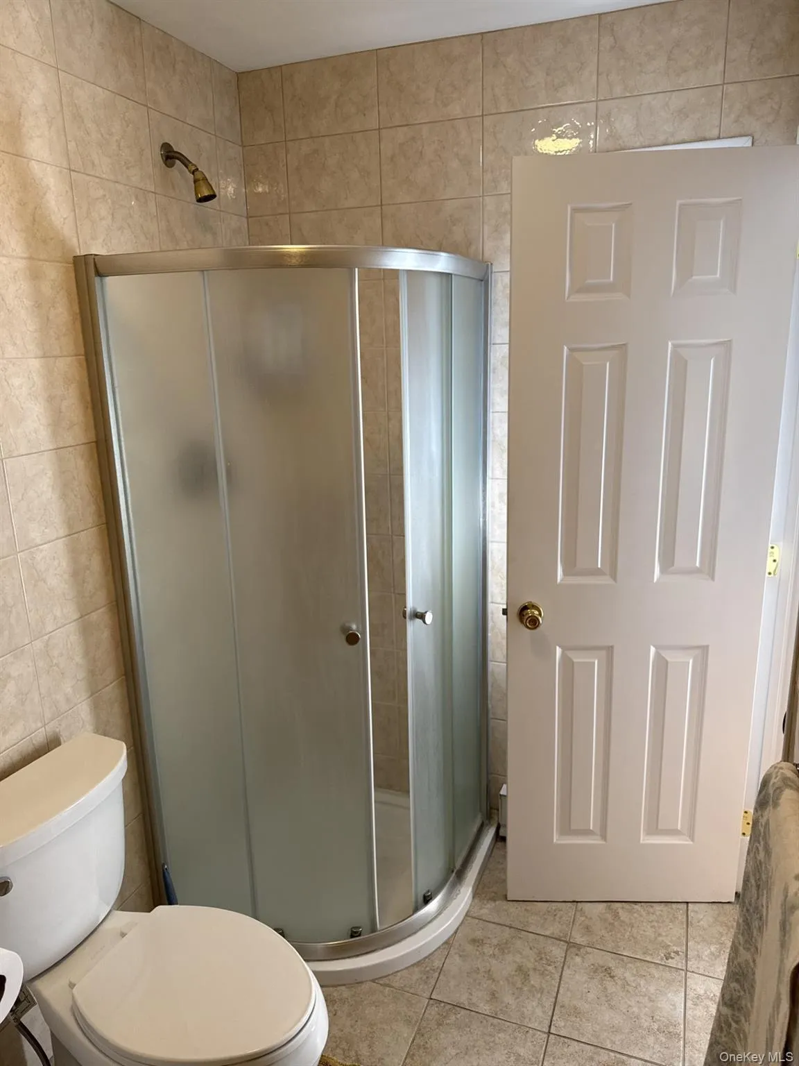 Bathroom featuring tile walls, a stall shower, and tile patterned flooring Bathroom featuring tile walls, a stall shower, and tile patterned flooring