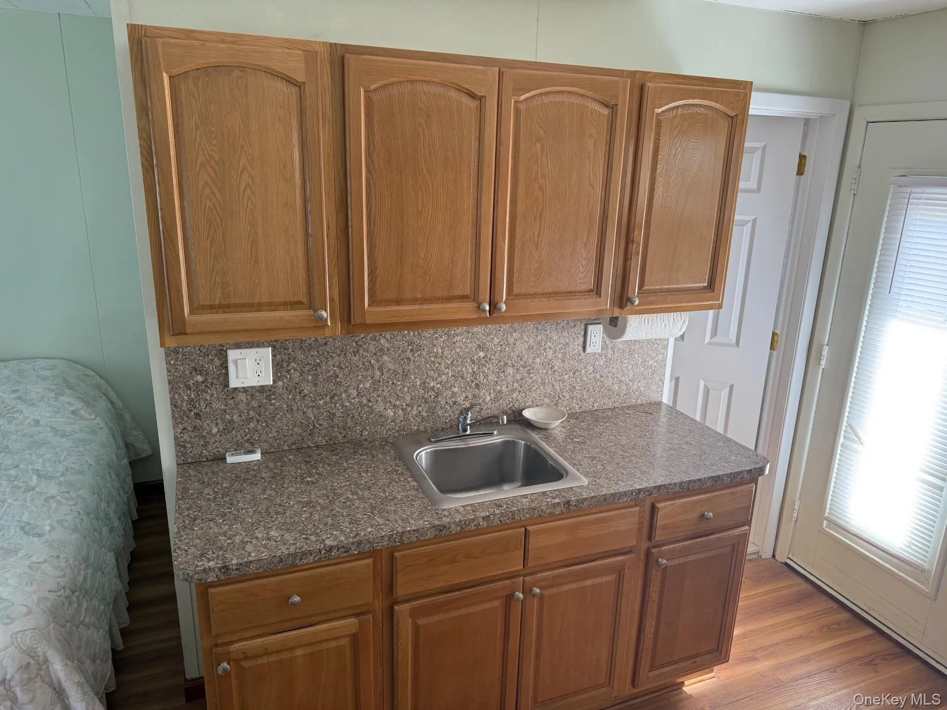 Kitchen with brown cabinets, tasteful backsplash, and dark wood-type flooring Kitchen with brown cabinets, tasteful backsplash, and dark wood-type flooring