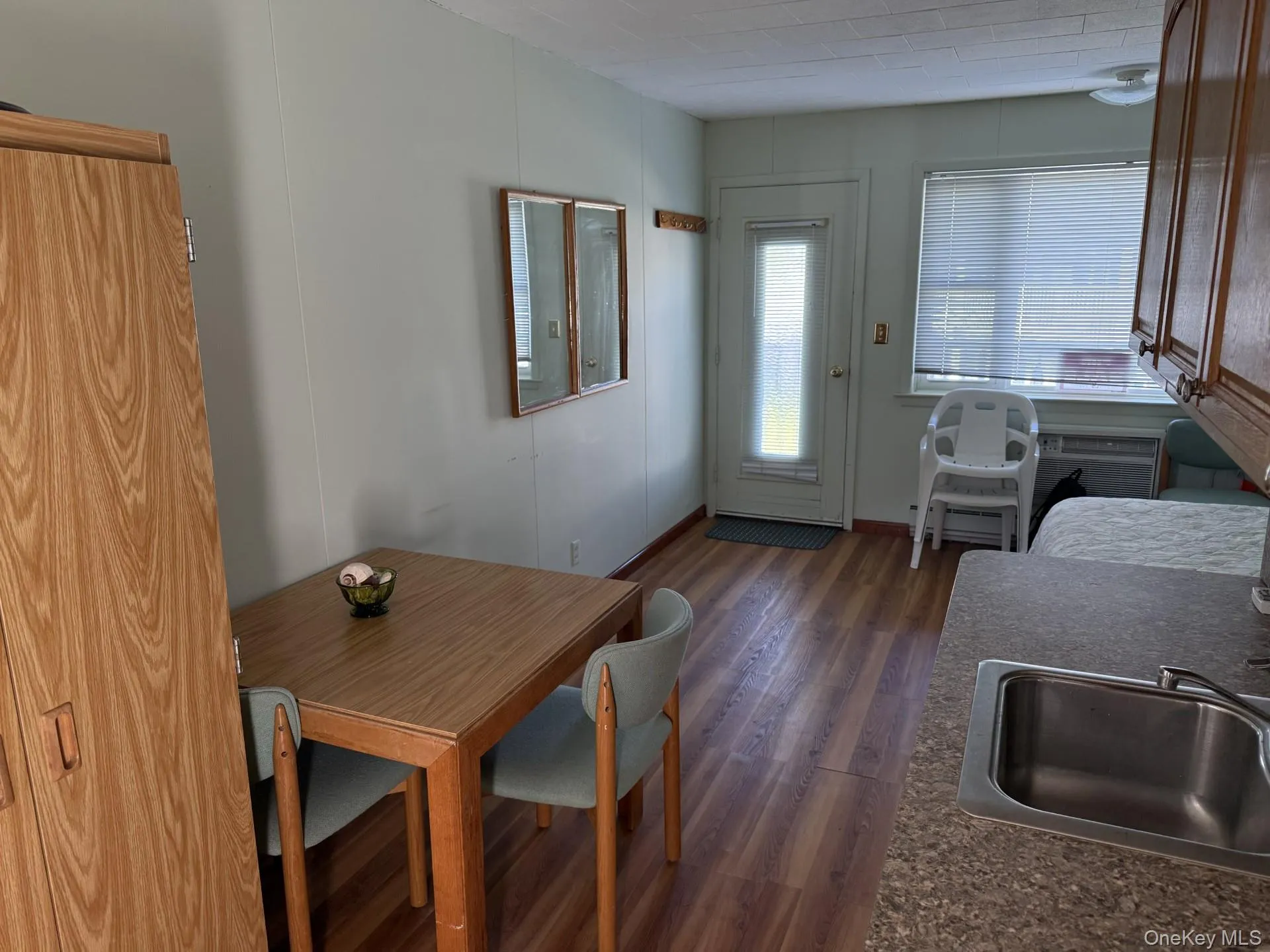 Dining area with dark wood-style floors and a decorative wall Dining area with dark wood-style floors and a decorative wall