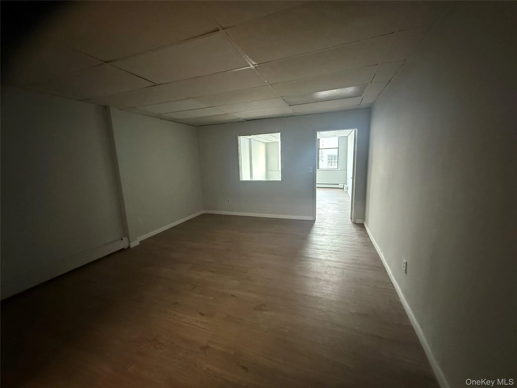 Spare room with a paneled ceiling, dark wood-style floors, and a baseboard radiator Spare room with a paneled ceiling, dark wood-style floors, and a baseboard radiator