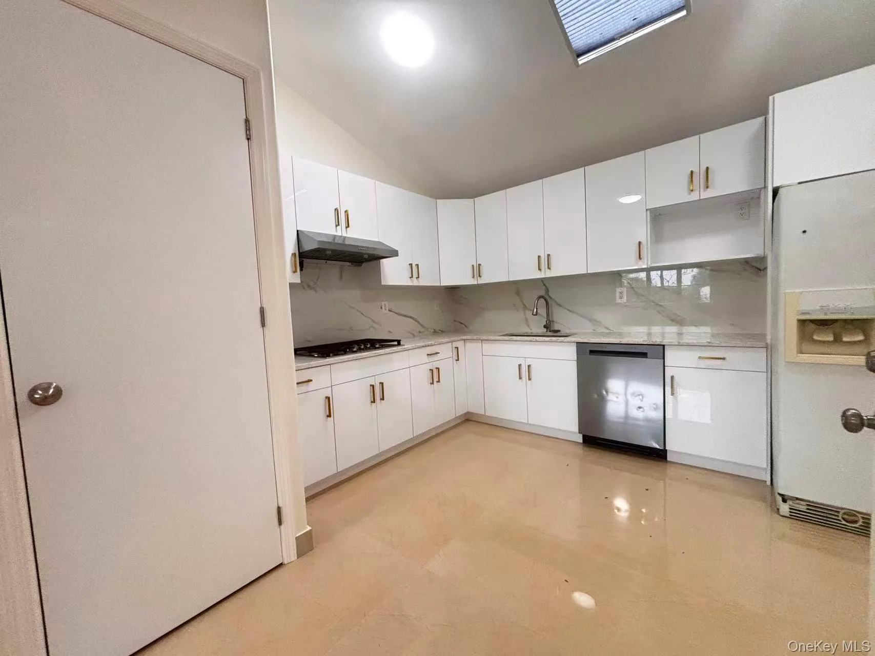Kitchen featuring decorative backsplash, white fridge with ice dispenser, white cabinetry, vaulted ceiling, and dishwasher Kitchen featuring decorative backsplash, white fridge with ice dispenser, white cabinetry, vaulted ceiling, and dishwasher