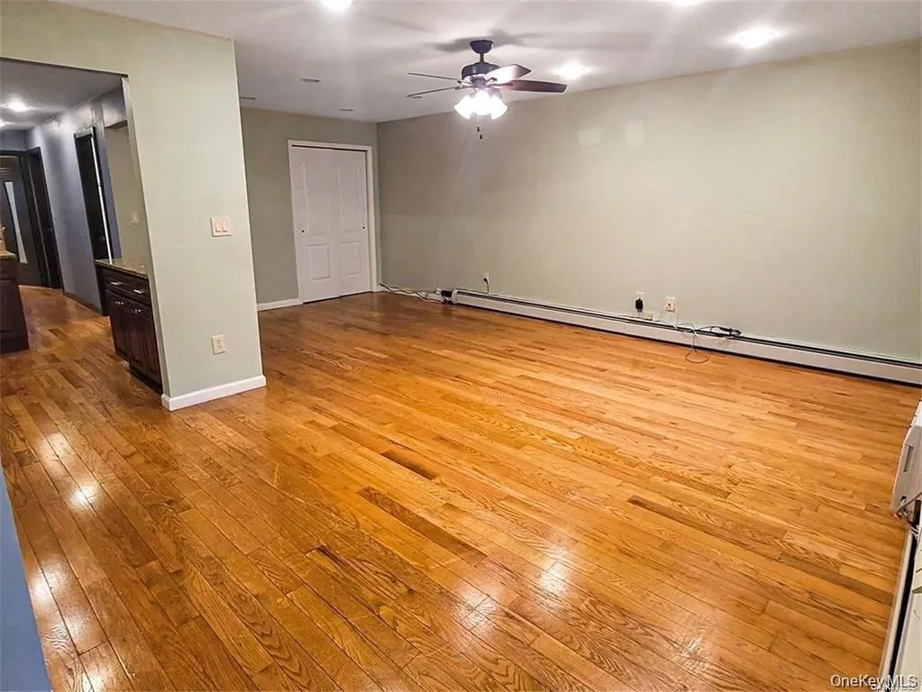 Empty room with a baseboard heating unit, light wood-type flooring, a ceiling fan, and recessed lighting Empty room with a baseboard heating unit, light wood-type flooring, a ceiling fan, and recessed lighting