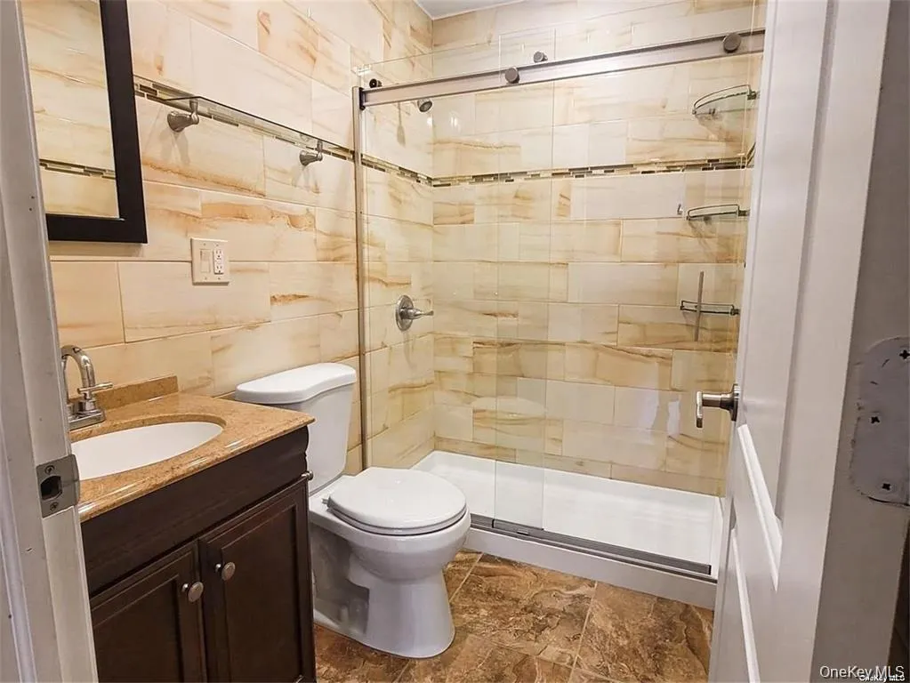 Bathroom featuring vanity, a stall shower, and stone finish flooring Bathroom featuring vanity, a stall shower, and stone finish flooring