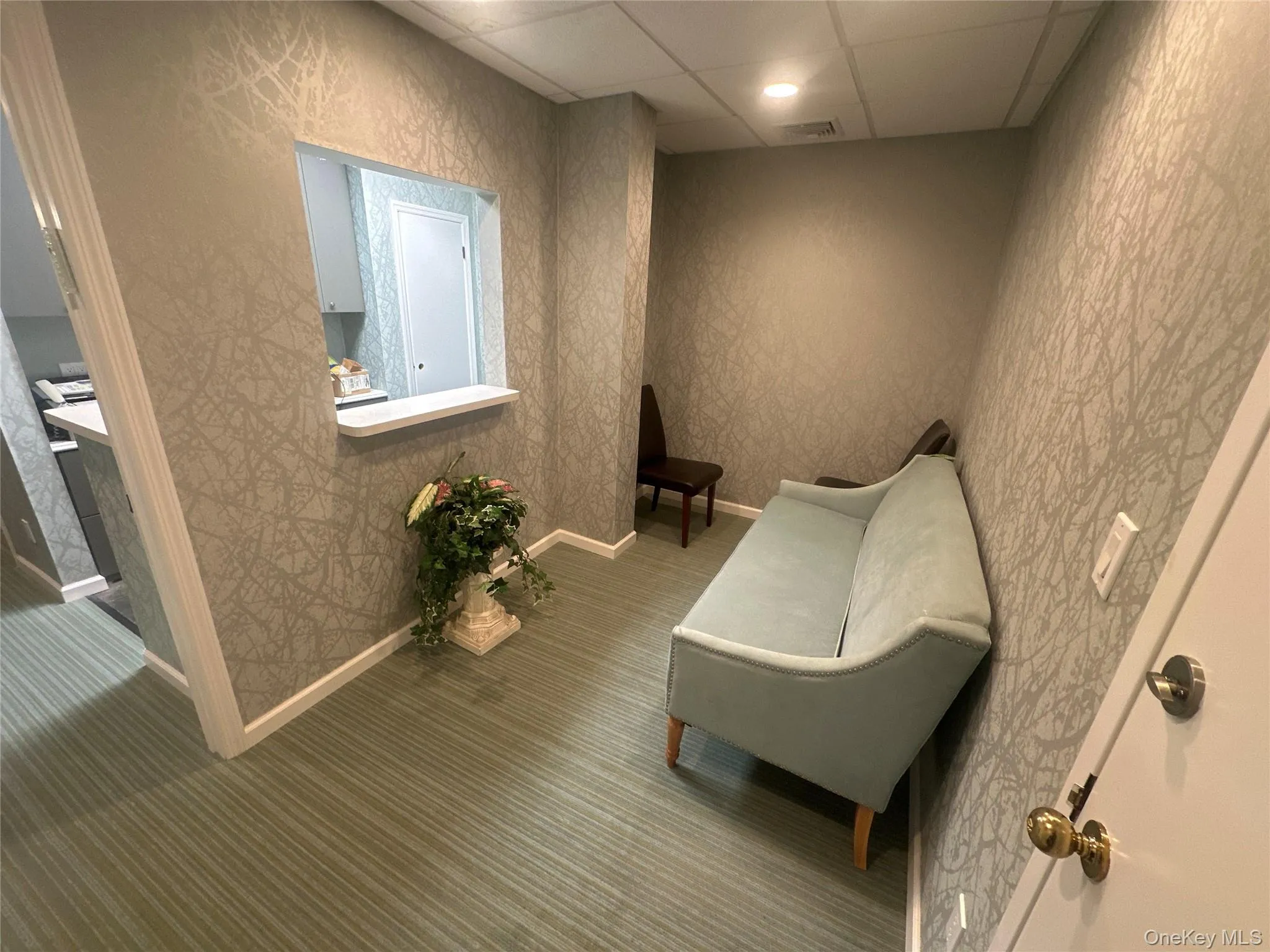 Living area with a paneled ceiling, recessed lighting, and wallpapered walls Living area with a paneled ceiling, recessed lighting, and wallpapered walls