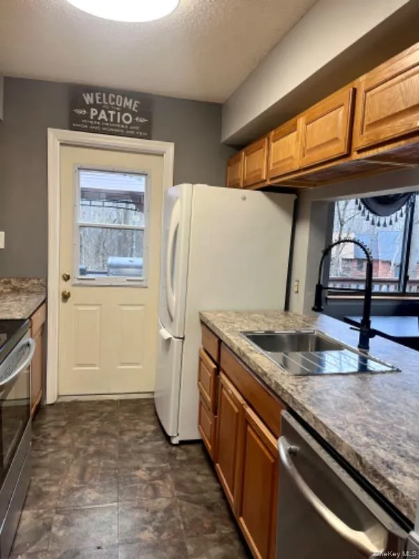 Kitchen with appliances with stainless steel finishes, a textured ceiling, and brown cabinets Kitchen with appliances with stainless steel finishes, a textured ceiling, and brown cabinets