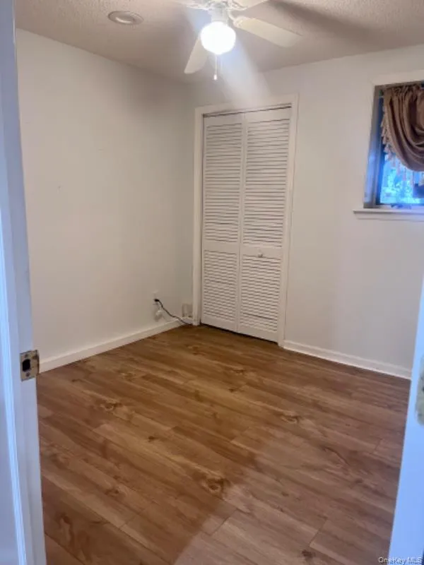 Unfurnished bedroom with a textured ceiling, dark wood finished floors, ceiling fan, and a closet Unfurnished bedroom with a textured ceiling, dark wood finished floors, ceiling fan, and a closet