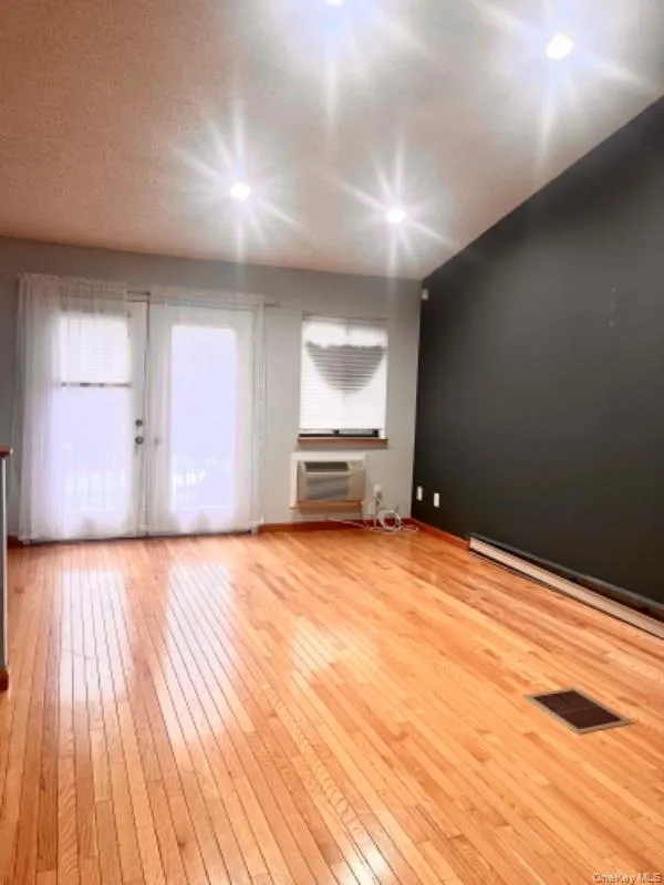 Unfurnished living room featuring light wood-style floors and a baseboard radiator Unfurnished living room featuring light wood-style floors and a baseboard radiator