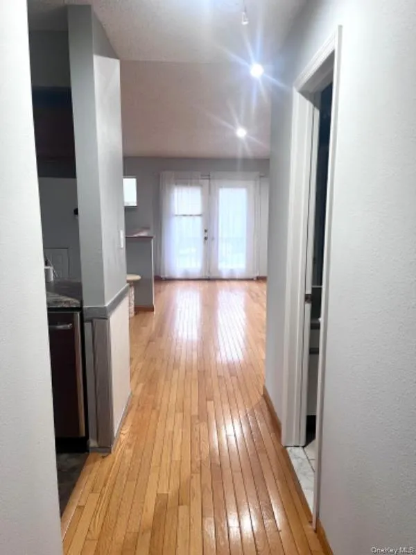 Hall featuring light wood-style flooring and french doors Hall featuring light wood-style flooring and french doors