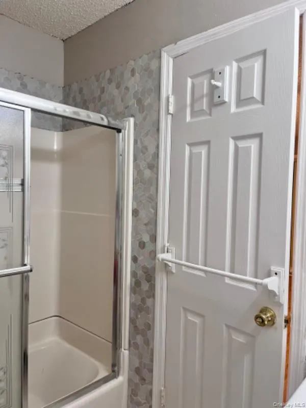 Full bathroom featuring a stall shower and a textured ceiling Full bathroom featuring a stall shower and a textured ceiling