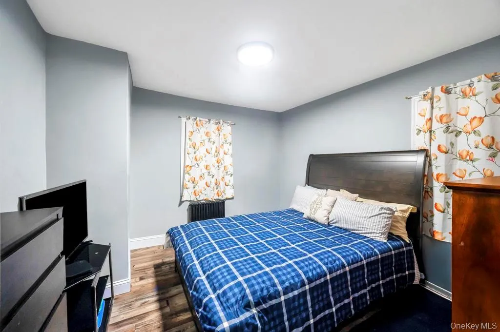 Bedroom with radiator heating unit and wood finished floors Bedroom with radiator heating unit and wood finished floors