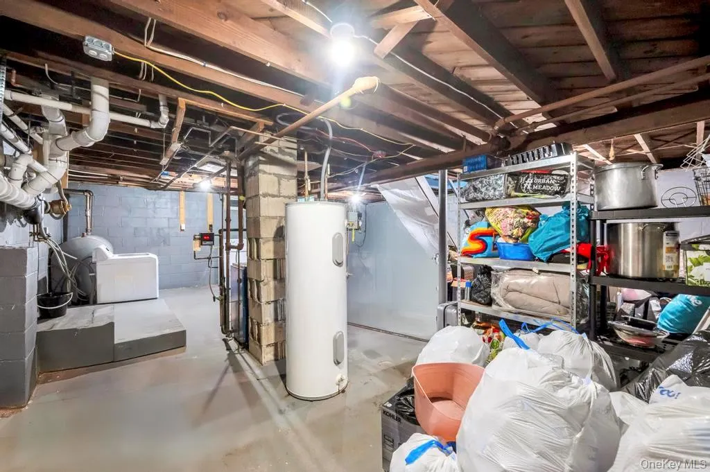 Unfinished below grade area featuring water heater and a heating unit Unfinished below grade area featuring water heater and a heating unit