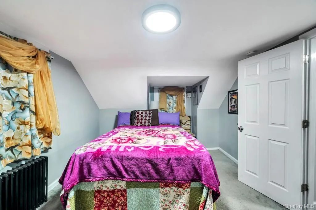 Carpeted bedroom featuring radiator heating unit and vaulted ceiling Carpeted bedroom featuring radiator heating unit and vaulted ceiling