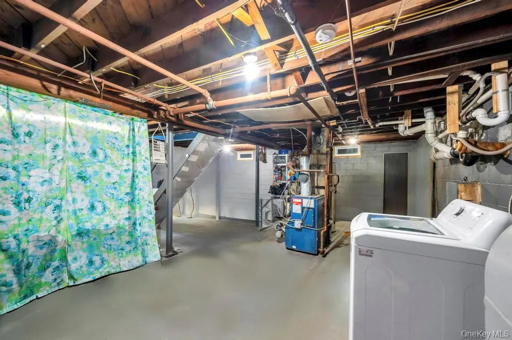 Unfinished below grade area with stairway, a heating unit, and separate washer and dryer Unfinished below grade area with stairway, a heating unit, and separate washer and dryer