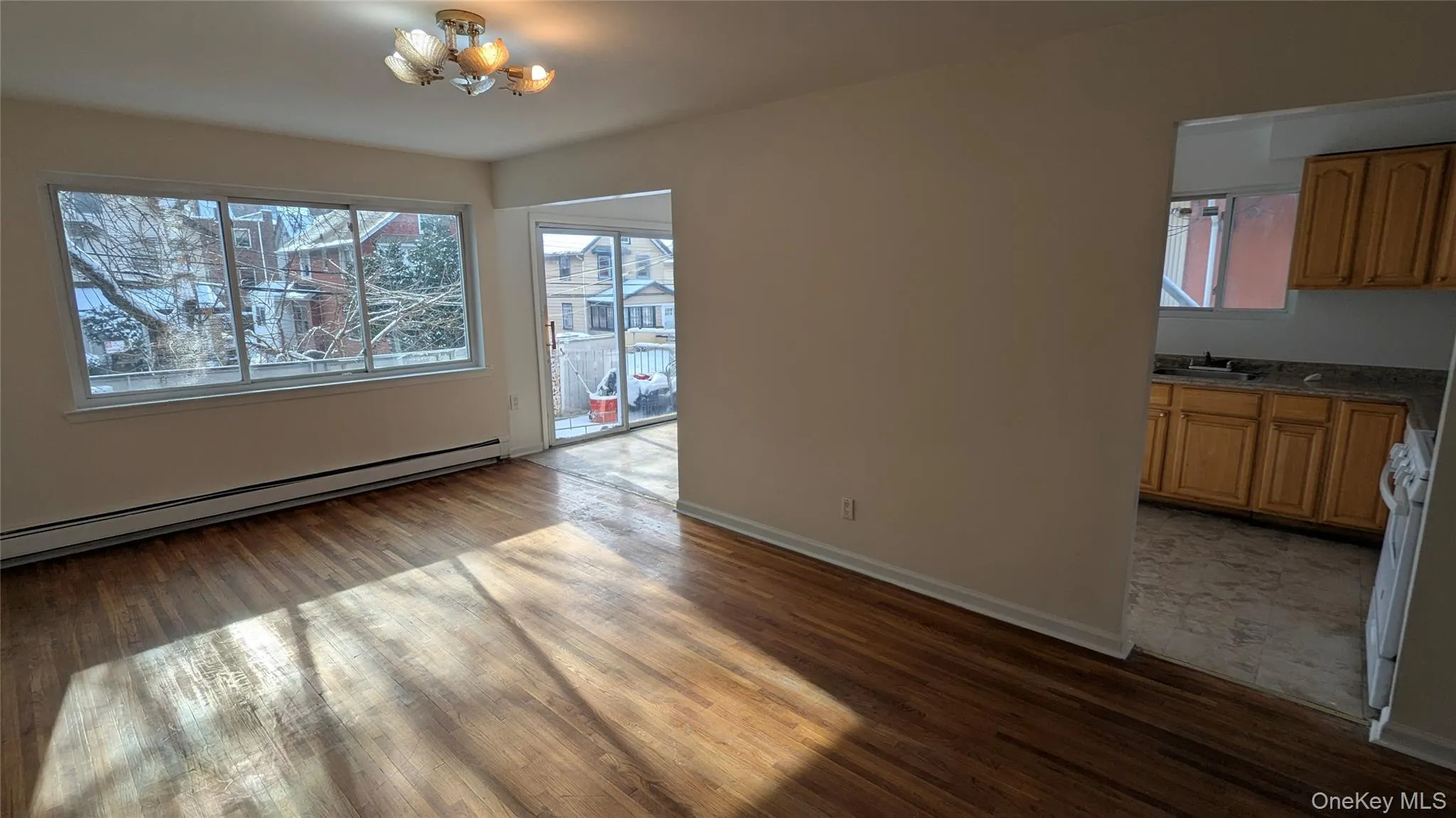 Unfurnished dining area with dark wood-type flooring, baseboard heating, plenty of natural light, and a chandelier Unfurnished dining area with dark wood-type flooring, baseboard heating, plenty of natural light, and a chandelier
