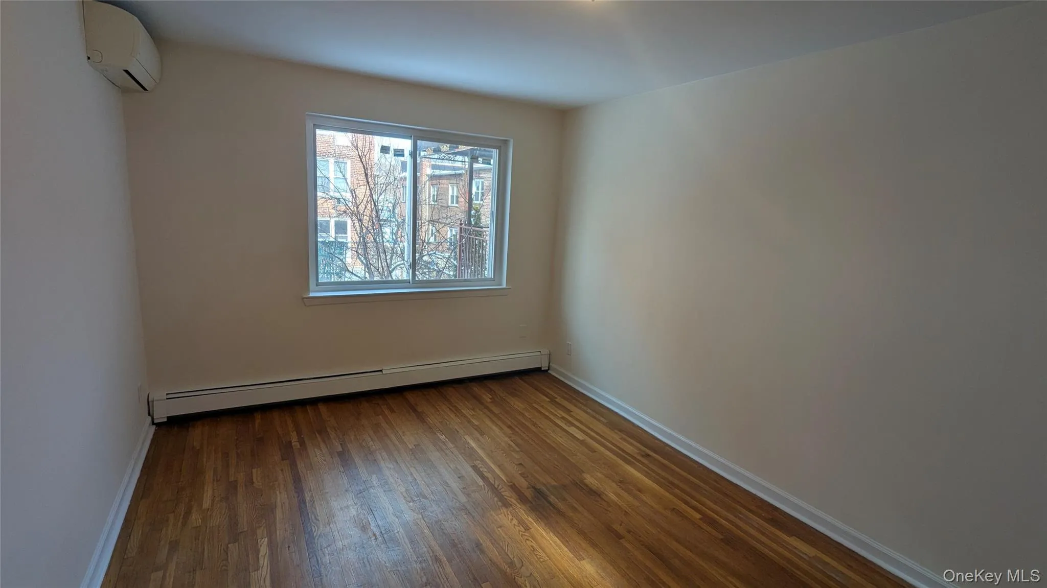 Spare room featuring hardwood / wood-style flooring, a baseboard heating unit, and a wall unit AC Spare room featuring hardwood / wood-style flooring, a baseboard heating unit, and a wall unit AC
