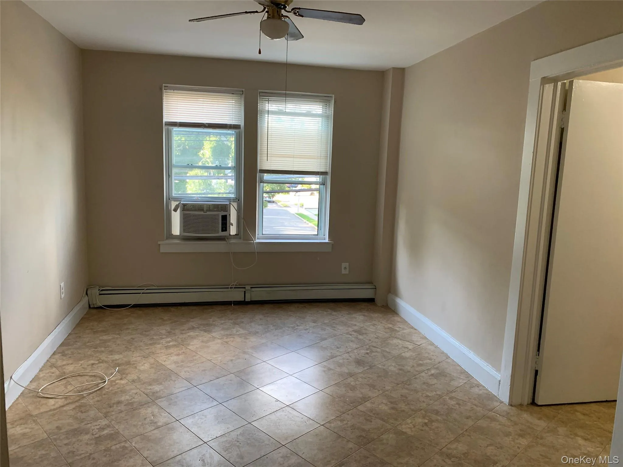 Empty room featuring a baseboard radiator, a ceiling fan, and cooling unit Empty room featuring a baseboard radiator, a ceiling fan, and cooling unit