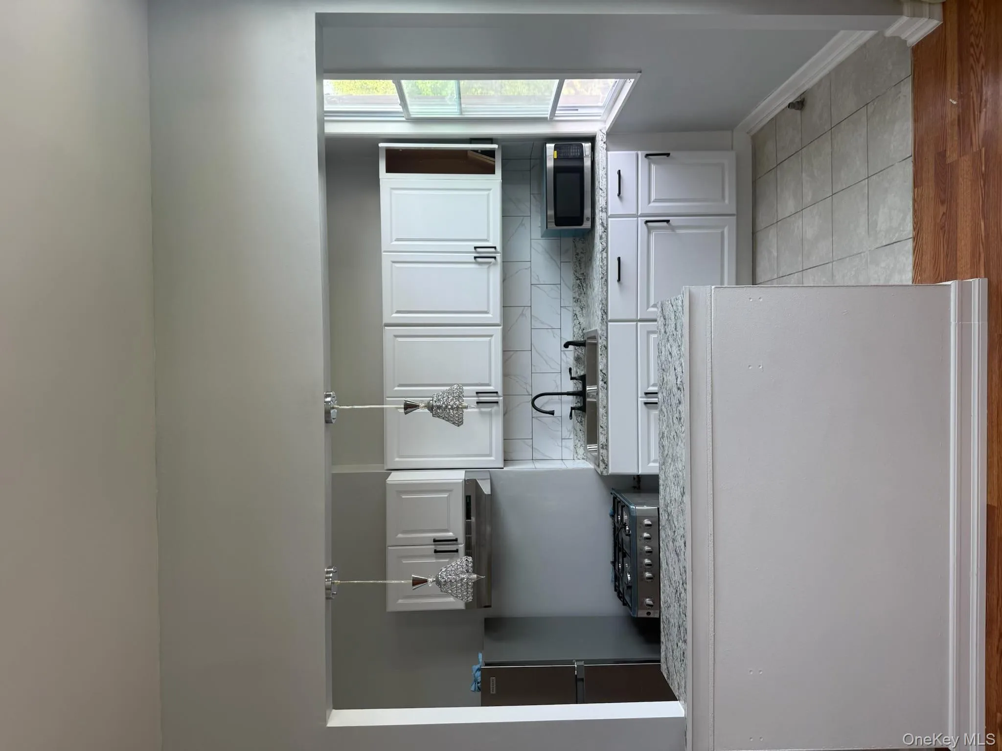 Kitchen featuring white cabinets, decorative backsplash, fridge, and white microwave Kitchen featuring white cabinets, decorative backsplash, fridge, and white microwave
