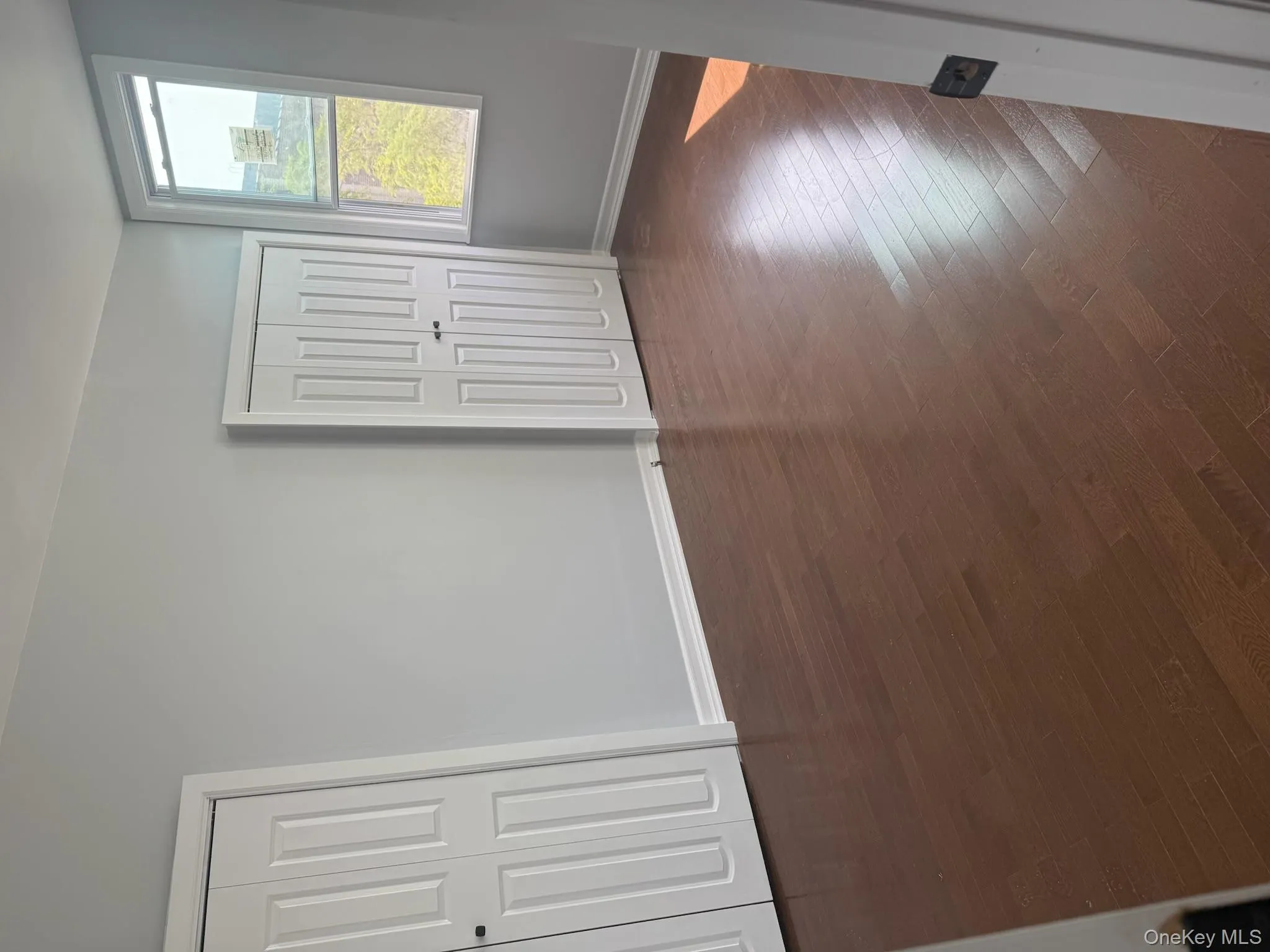 Well lit master bedroom multiple closets and dark wood-style floors Well lit master bedroom multiple closets and dark wood-style floors