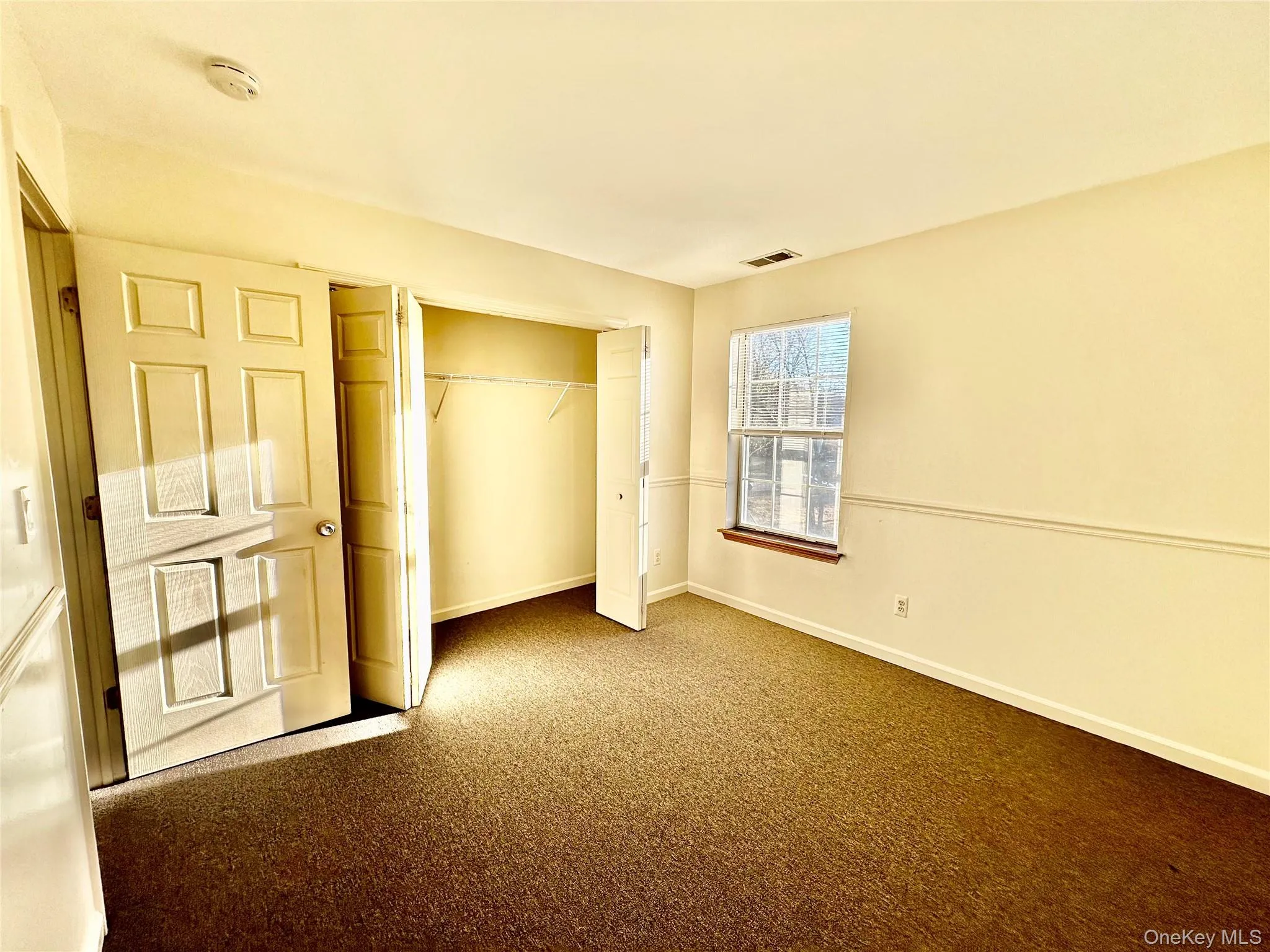 Second bedroom with double closet featuring dark colored carpet and a wealth of natural light Second bedroom with double closet featuring dark colored carpet and a wealth of natural light
