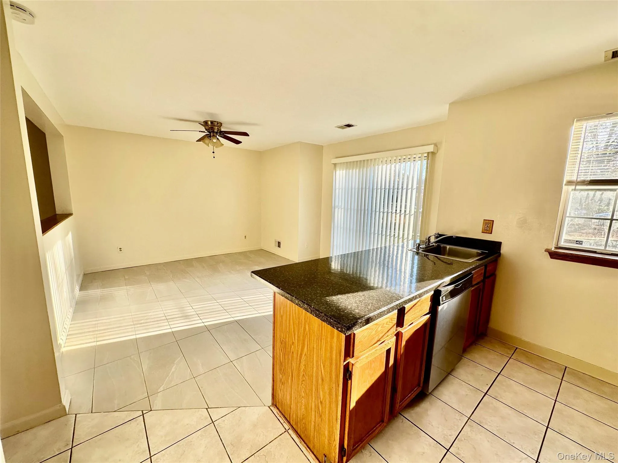 Kitchen featuring kitchen peninsula, stainless steel dishwasher, ceiling fan, sink, and light tile patterned floors Kitchen featuring kitchen peninsula, stainless steel dishwasher, ceiling fan, sink, and light tile patterned floors