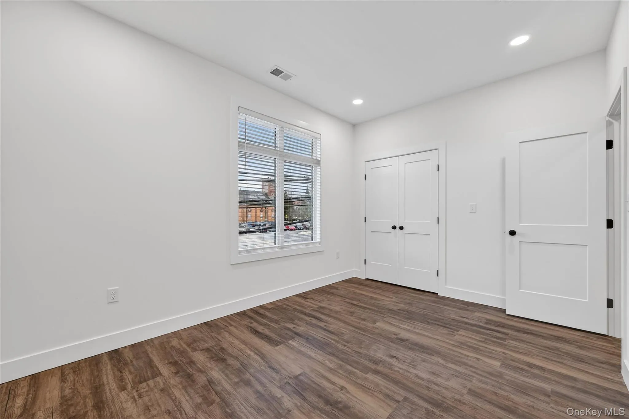 Unfurnished bedroom with dark wood-style flooring, recessed lighting, and a closet Unfurnished bedroom with dark wood-style flooring, recessed lighting, and a closet