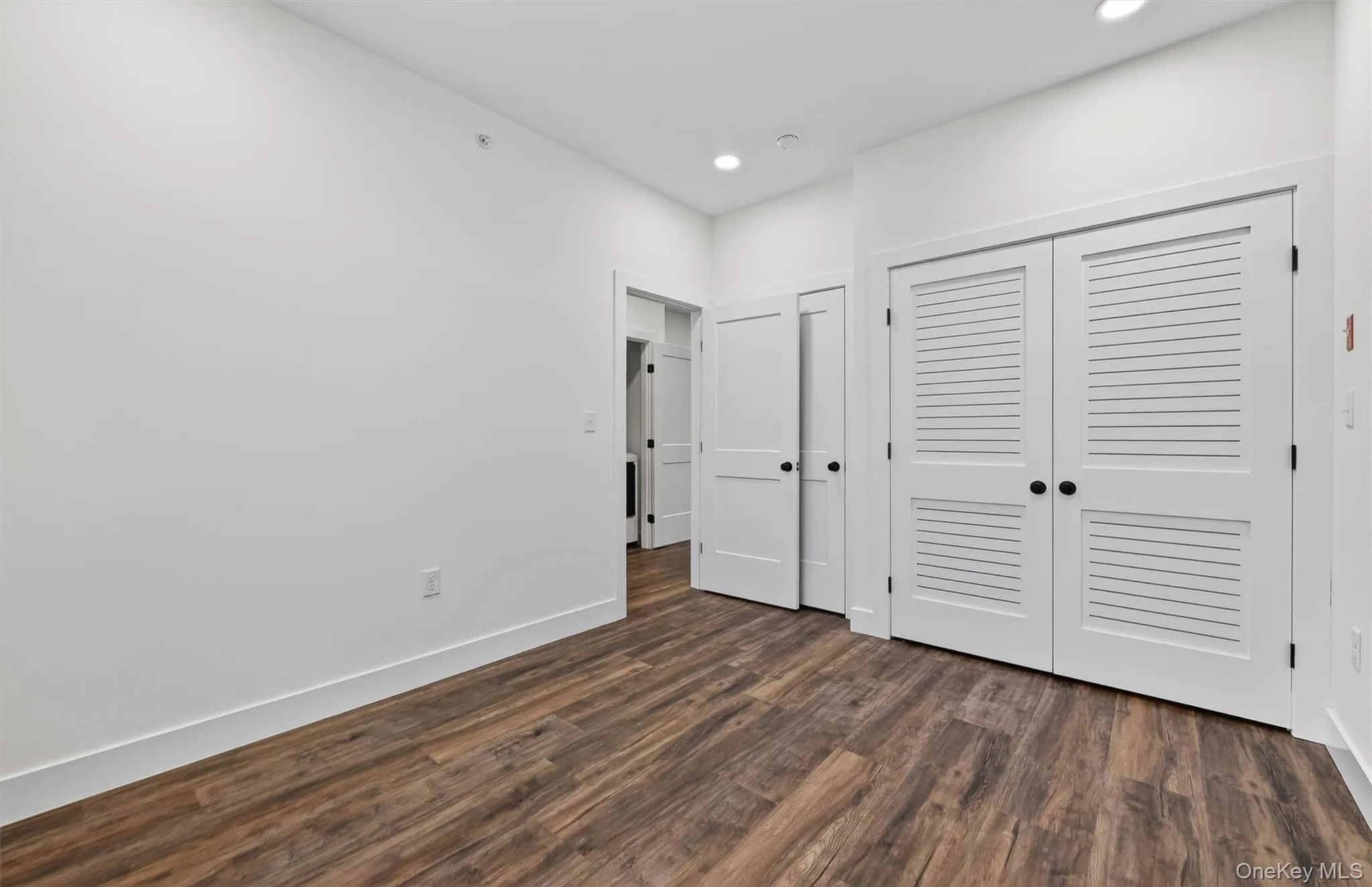 Unfurnished bedroom with dark wood-style floors, a closet, and recessed lighting Unfurnished bedroom with dark wood-style floors, a closet, and recessed lighting