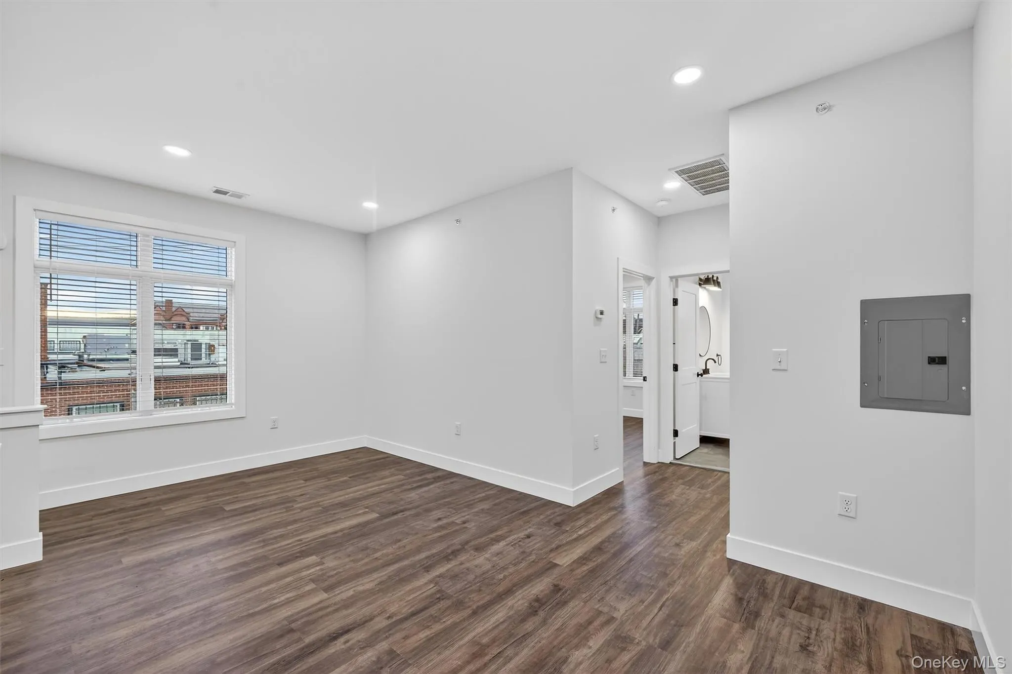 Empty room featuring dark wood-style flooring, electric panel, and recessed lighting Empty room featuring dark wood-style flooring, electric panel, and recessed lighting