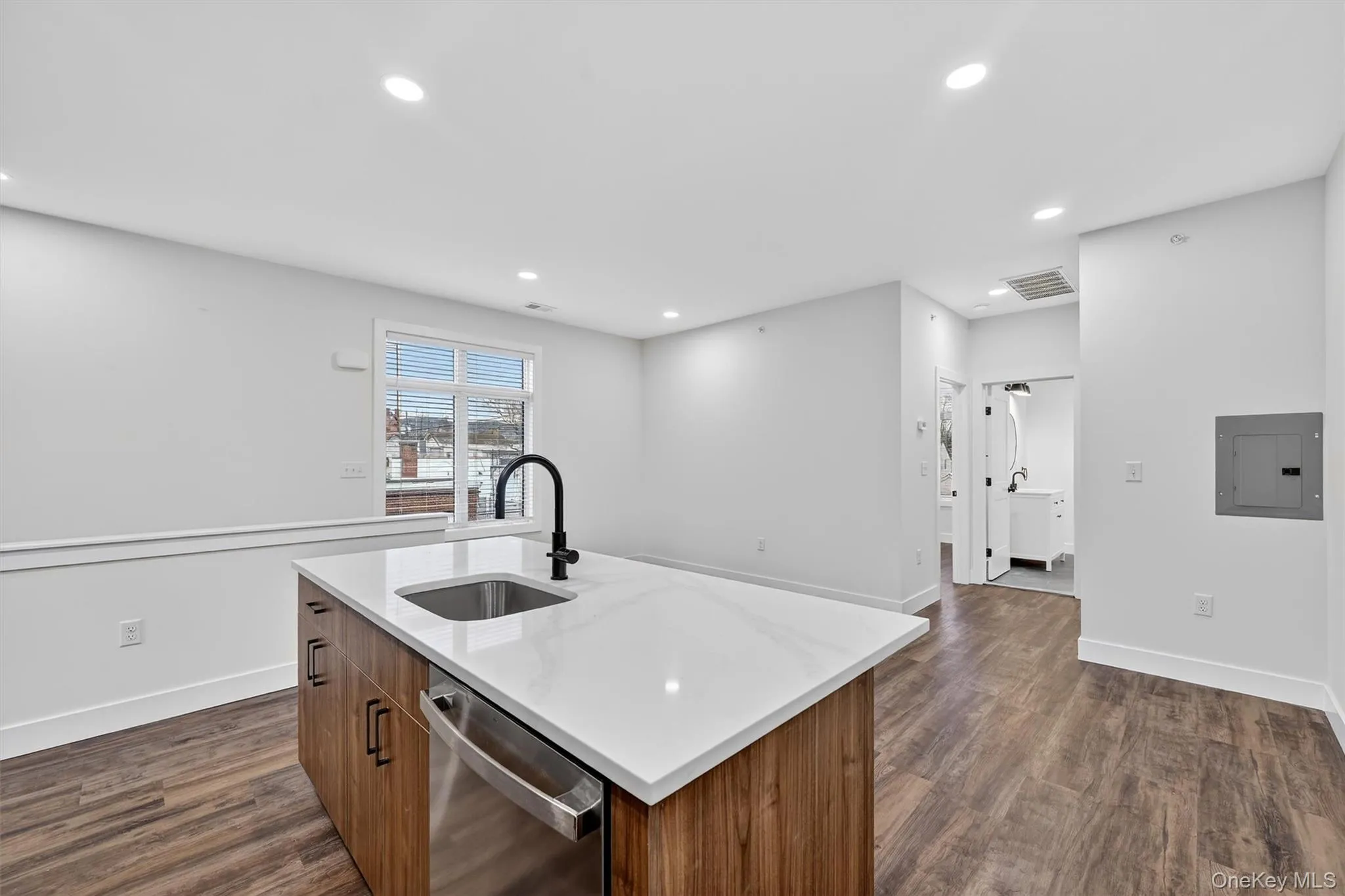 Kitchen featuring brown cabinetry, dishwasher, recessed lighting, dark wood-style floors, and electric panel Kitchen featuring brown cabinetry, dishwasher, recessed lighting, dark wood-style floors, and electric panel