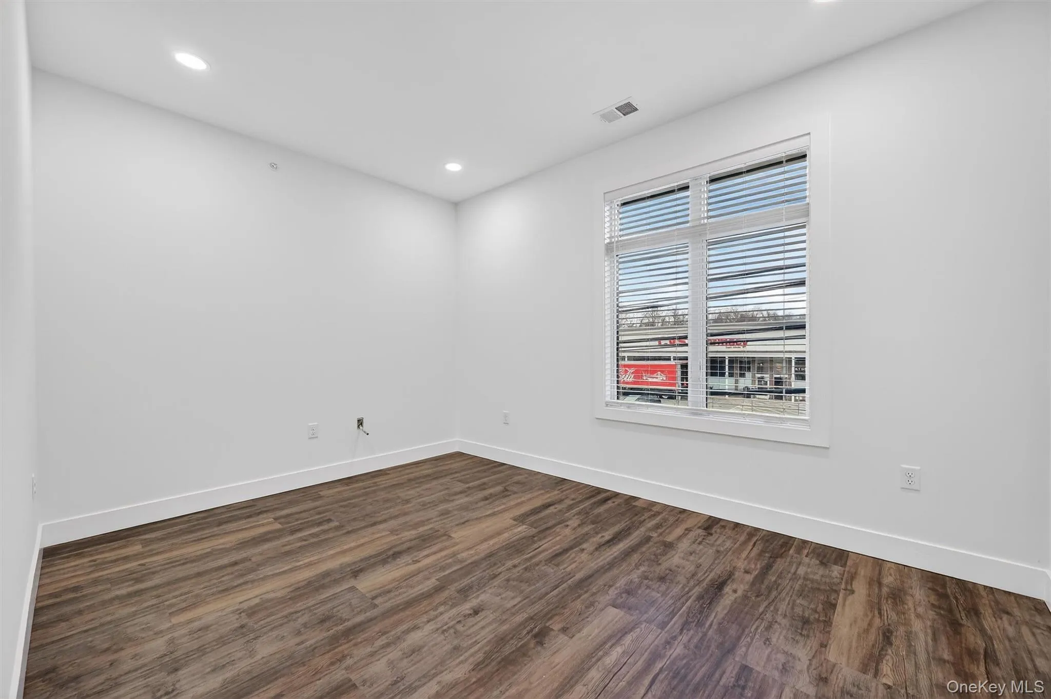Unfurnished room with dark wood-style flooring and recessed lighting Unfurnished room with dark wood-style flooring and recessed lighting