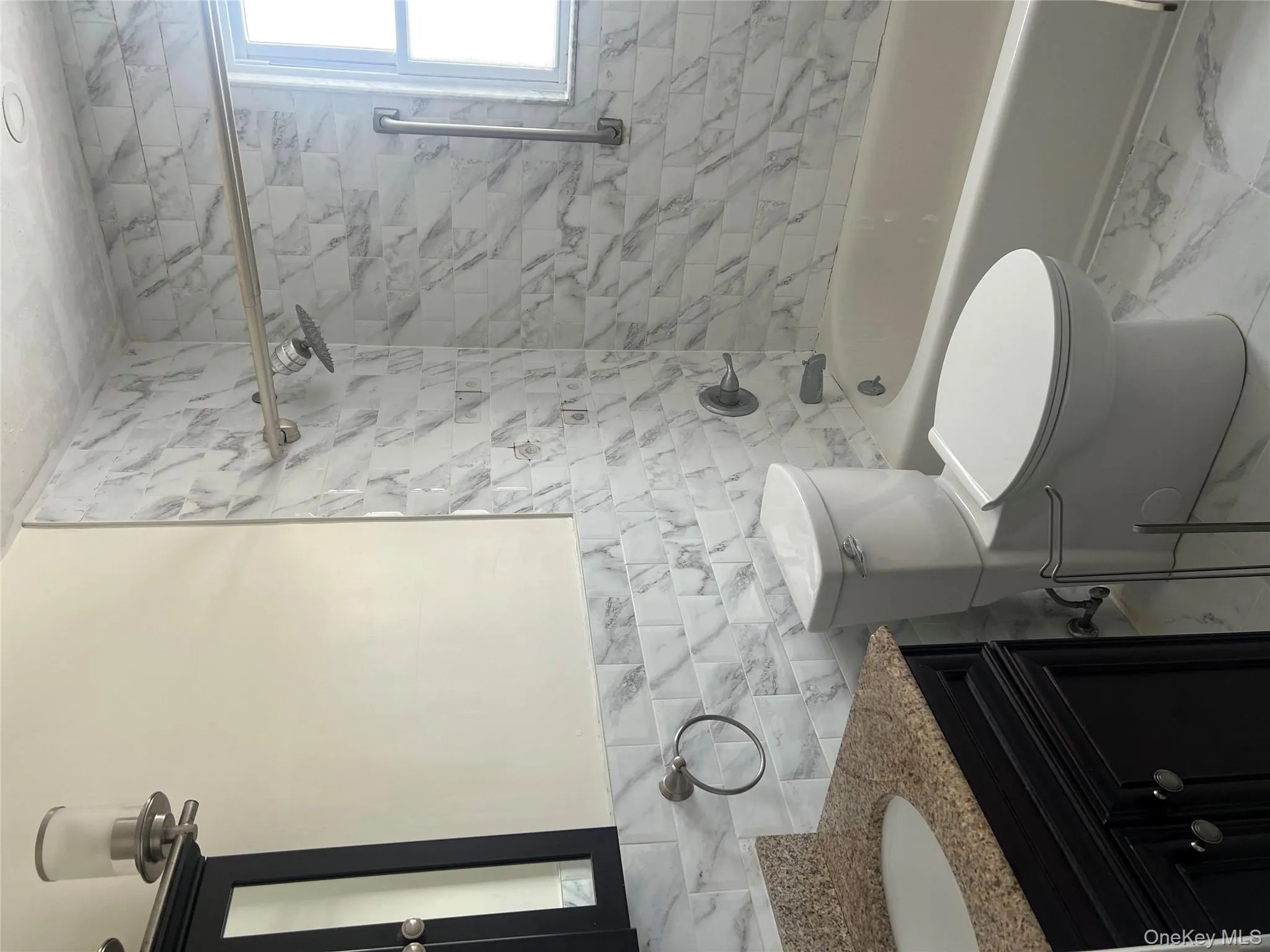 Bathroom featuring tile walls, washtub / shower combination, vanity, and marble finish flooring Bathroom featuring tile walls, washtub / shower combination, vanity, and marble finish flooring