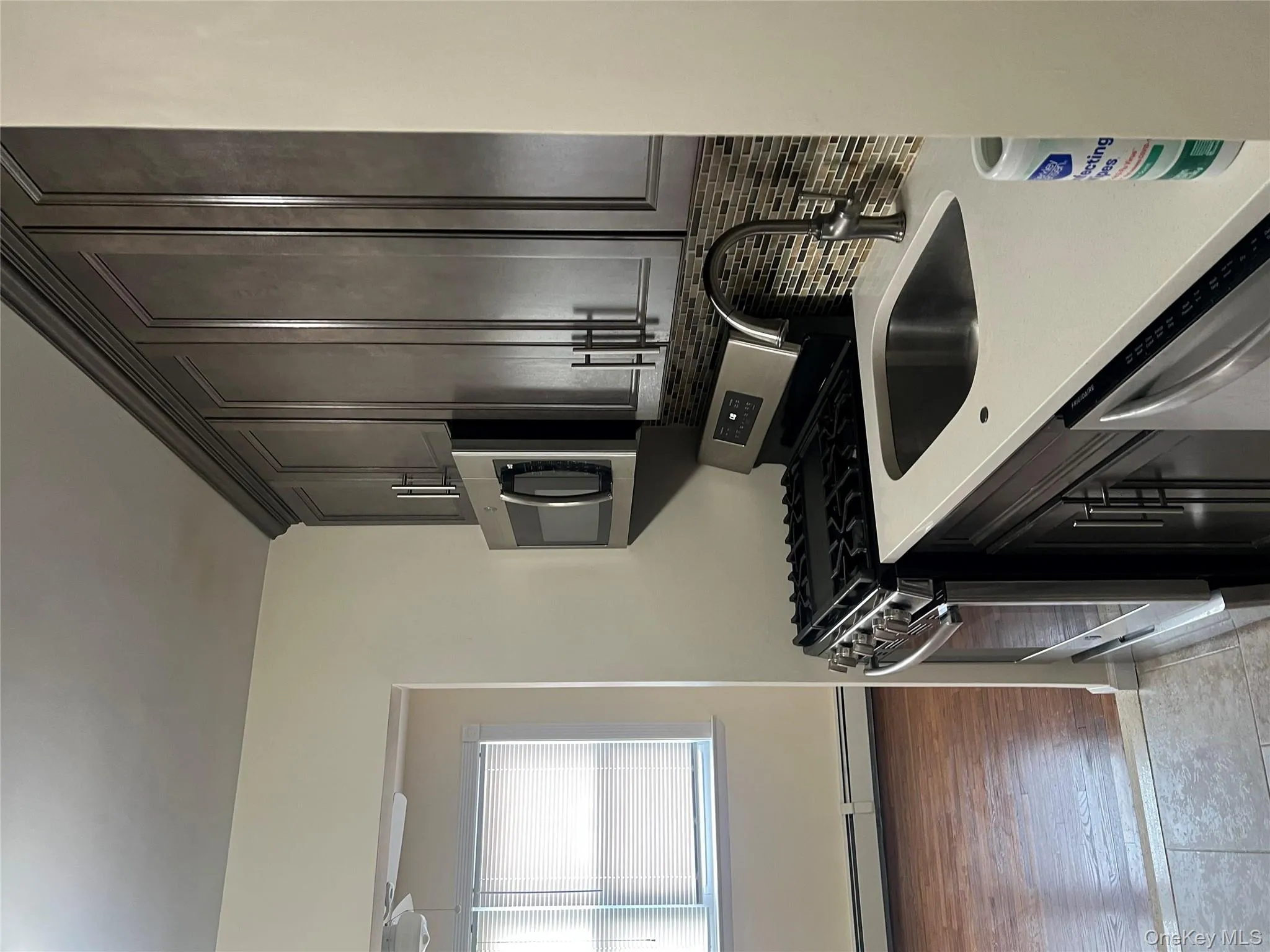 Kitchen with range, stainless steel microwave, light stone countertops, a baseboard heating unit, and dishwashing machine Kitchen with range, stainless steel microwave, light stone countertops, a baseboard heating unit, and dishwashing machine