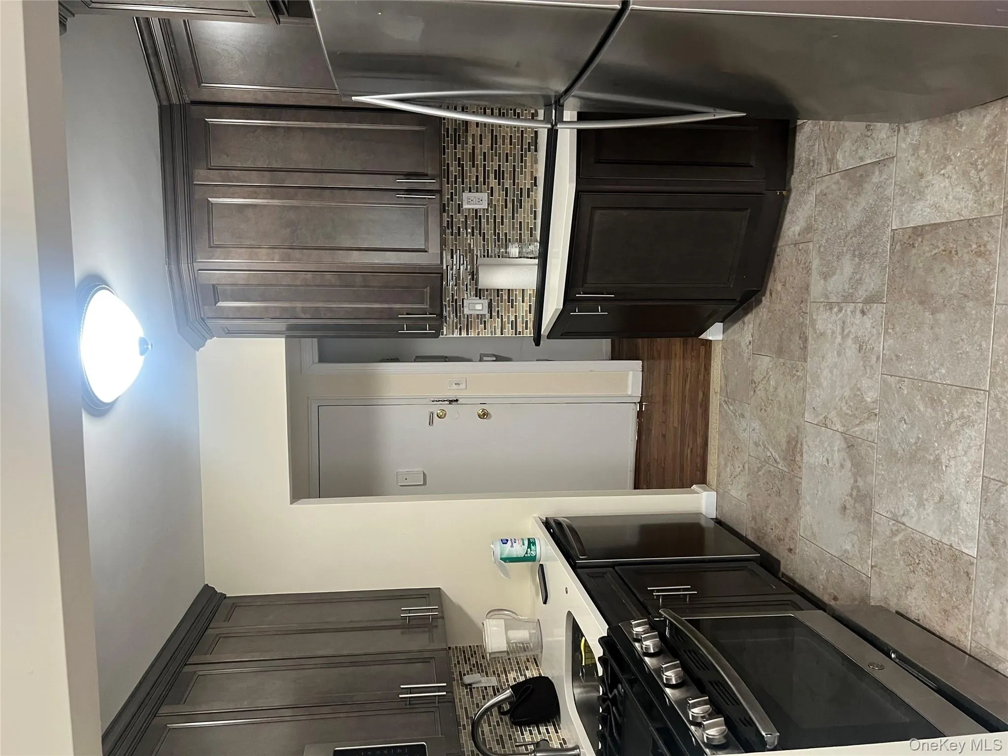 Kitchen with range, refrigerator, backsplash, and dark brown cabinetry Kitchen with range, refrigerator, backsplash, and dark brown cabinetry