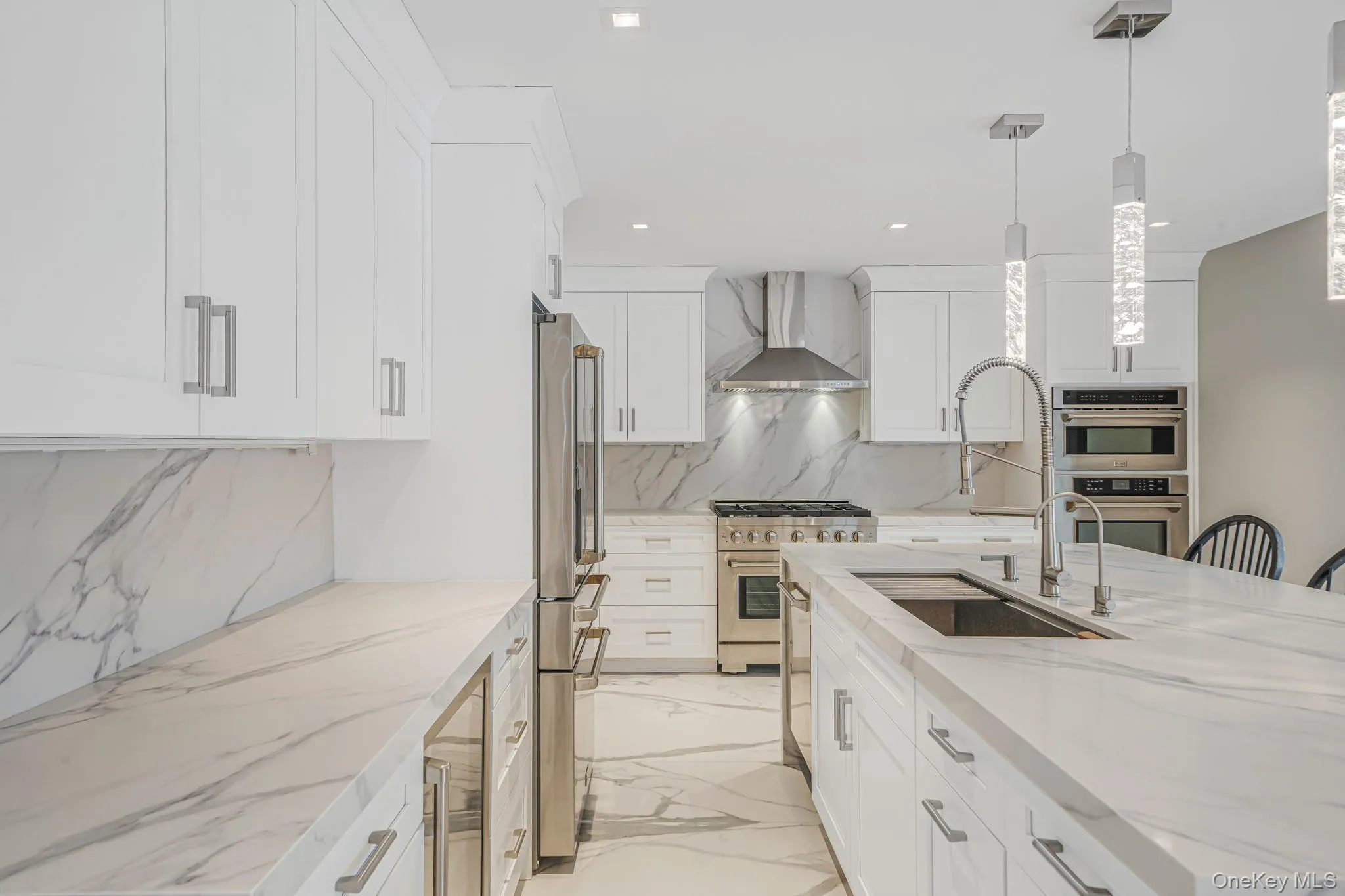 Kitchen featuring pendant lighting, light stone countertops, light marble finish flooring, backsplash, and high quality appliances Kitchen featuring pendant lighting, light stone countertops, light marble finish flooring, backsplash, and high quality appliances