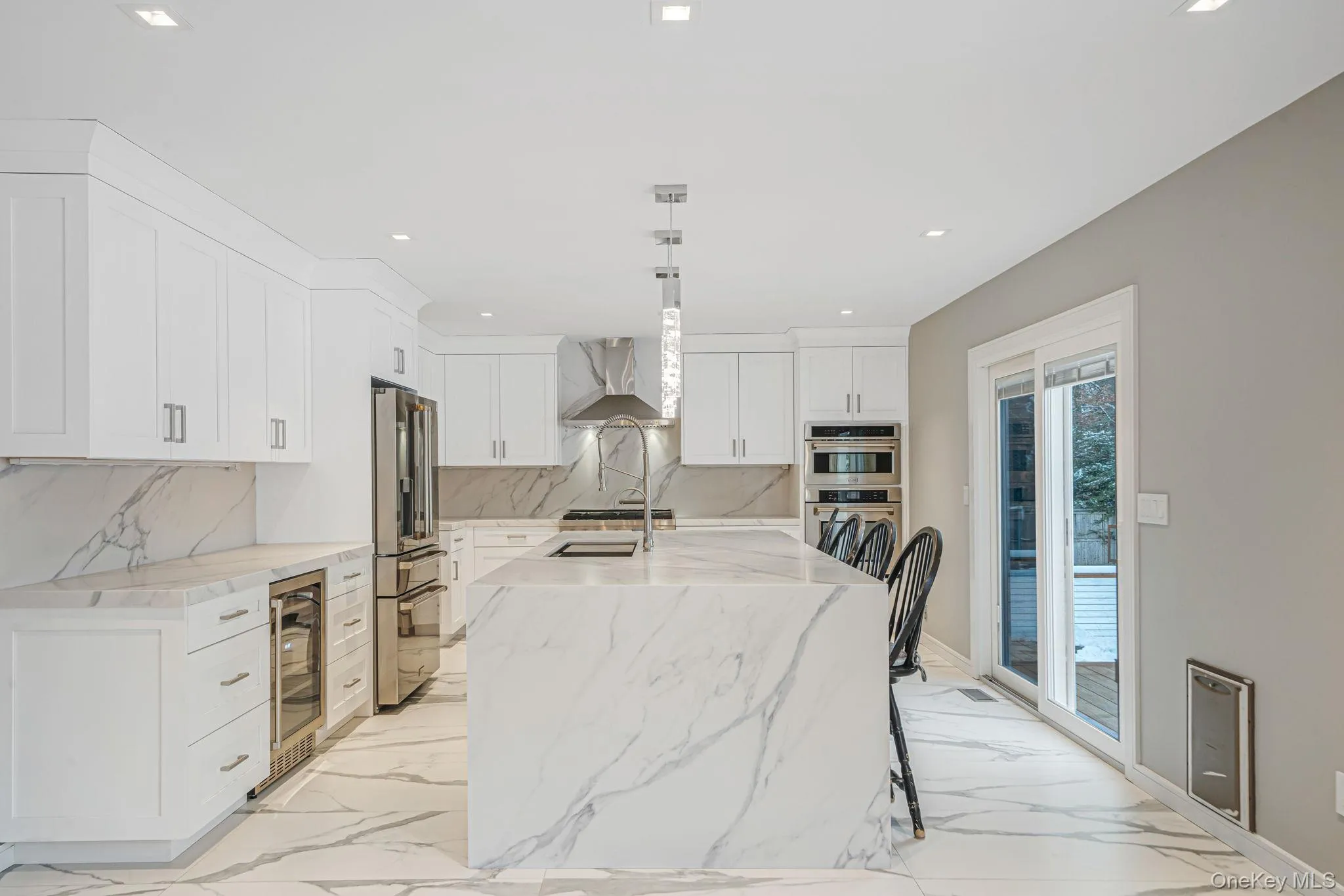 Kitchen featuring light stone countertops, hanging light fixtures, white cabinets, light marble finish floors, and recessed lighting Kitchen featuring light stone countertops, hanging light fixtures, white cabinets, light marble finish floors, and recessed lighting