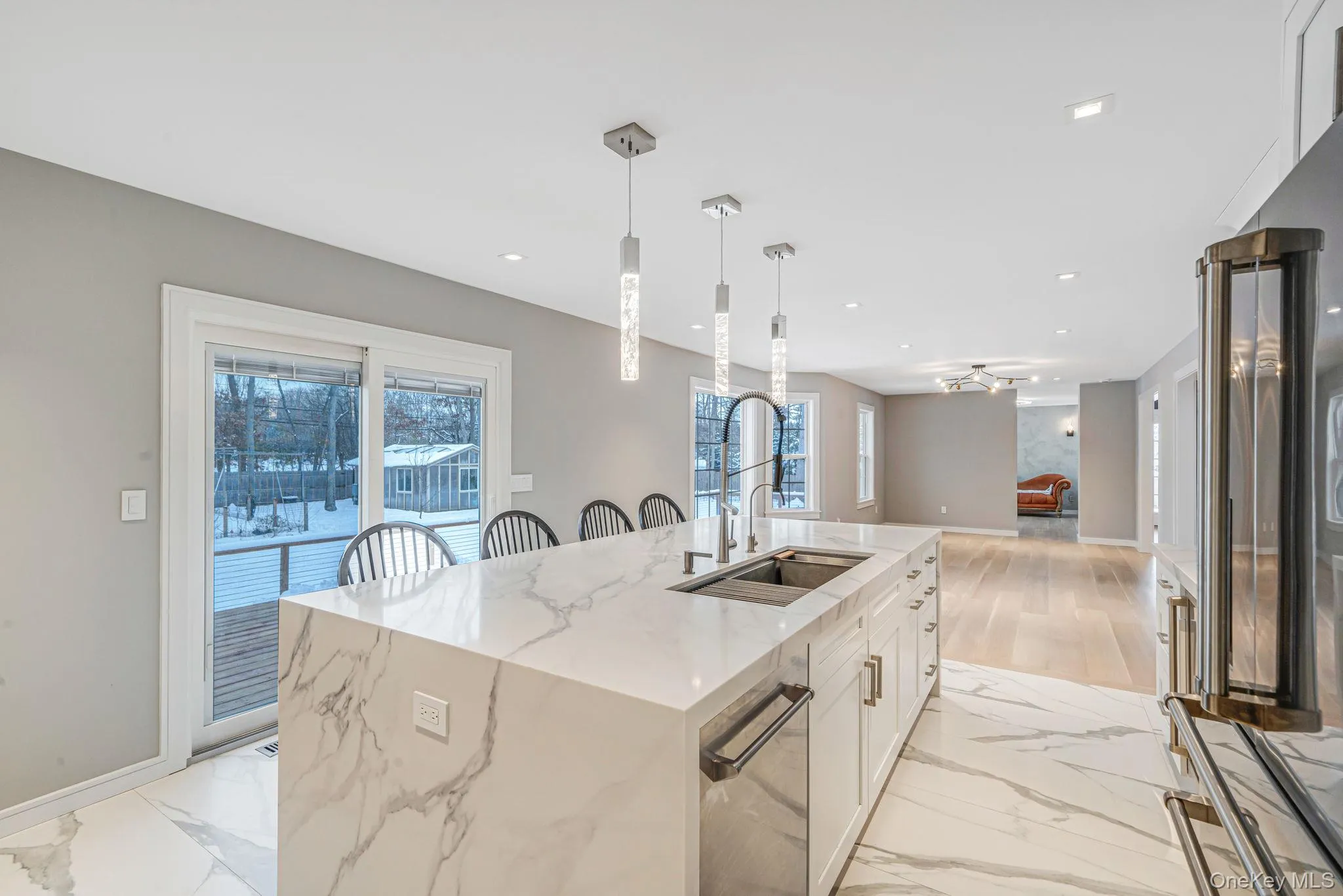 Kitchen with white cabinetry, light stone counters, stainless steel appliances, light marble finish floors, and pendant lighting Kitchen with white cabinetry, light stone counters, stainless steel appliances, light marble finish floors, and pendant lighting