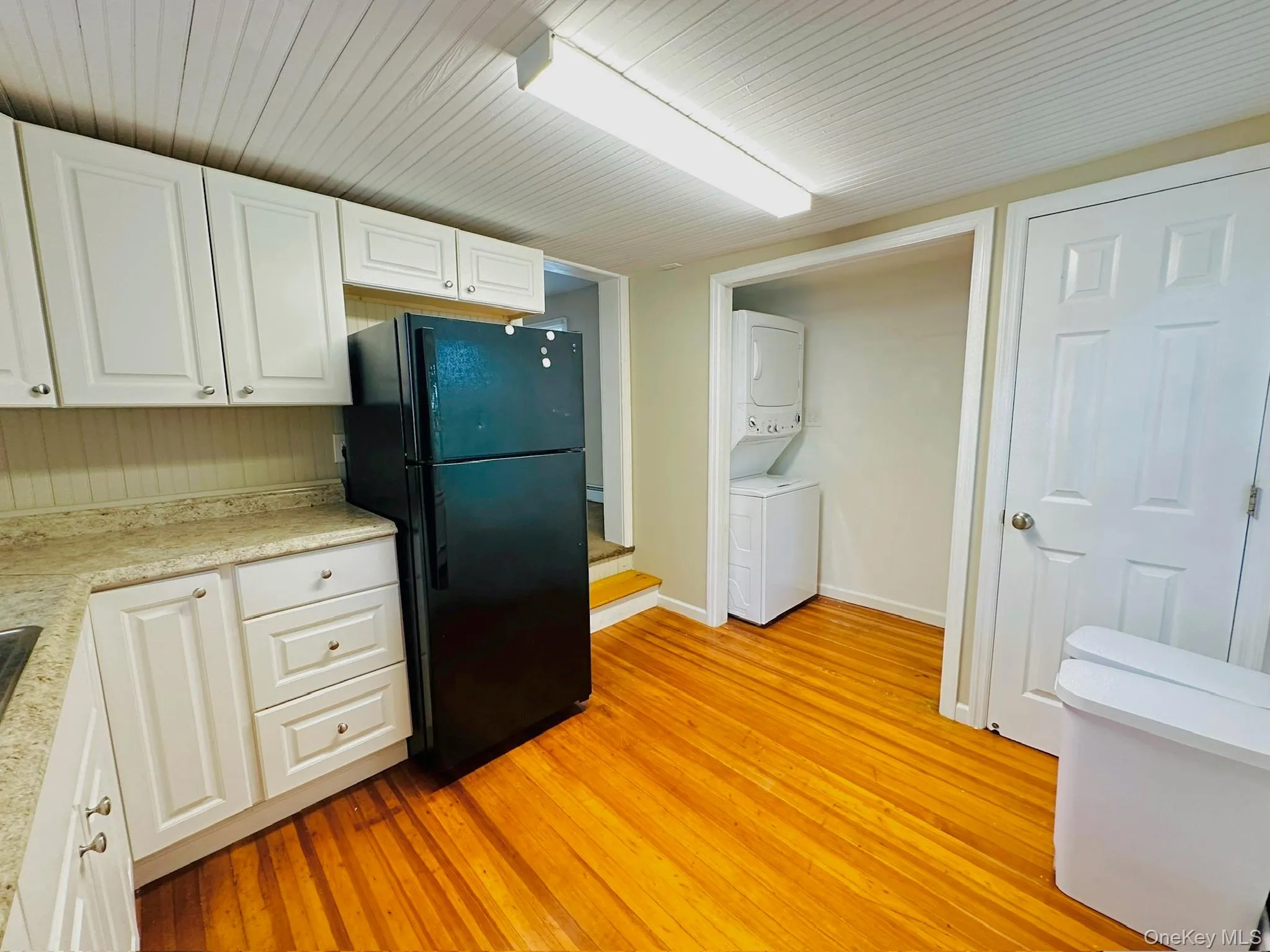 Kitchen with white cabinets, freestanding refrigerator, light countertops, light wood finished floors, and wood ceiling Kitchen with white cabinets, freestanding refrigerator, light countertops, light wood finished floors, and wood ceiling