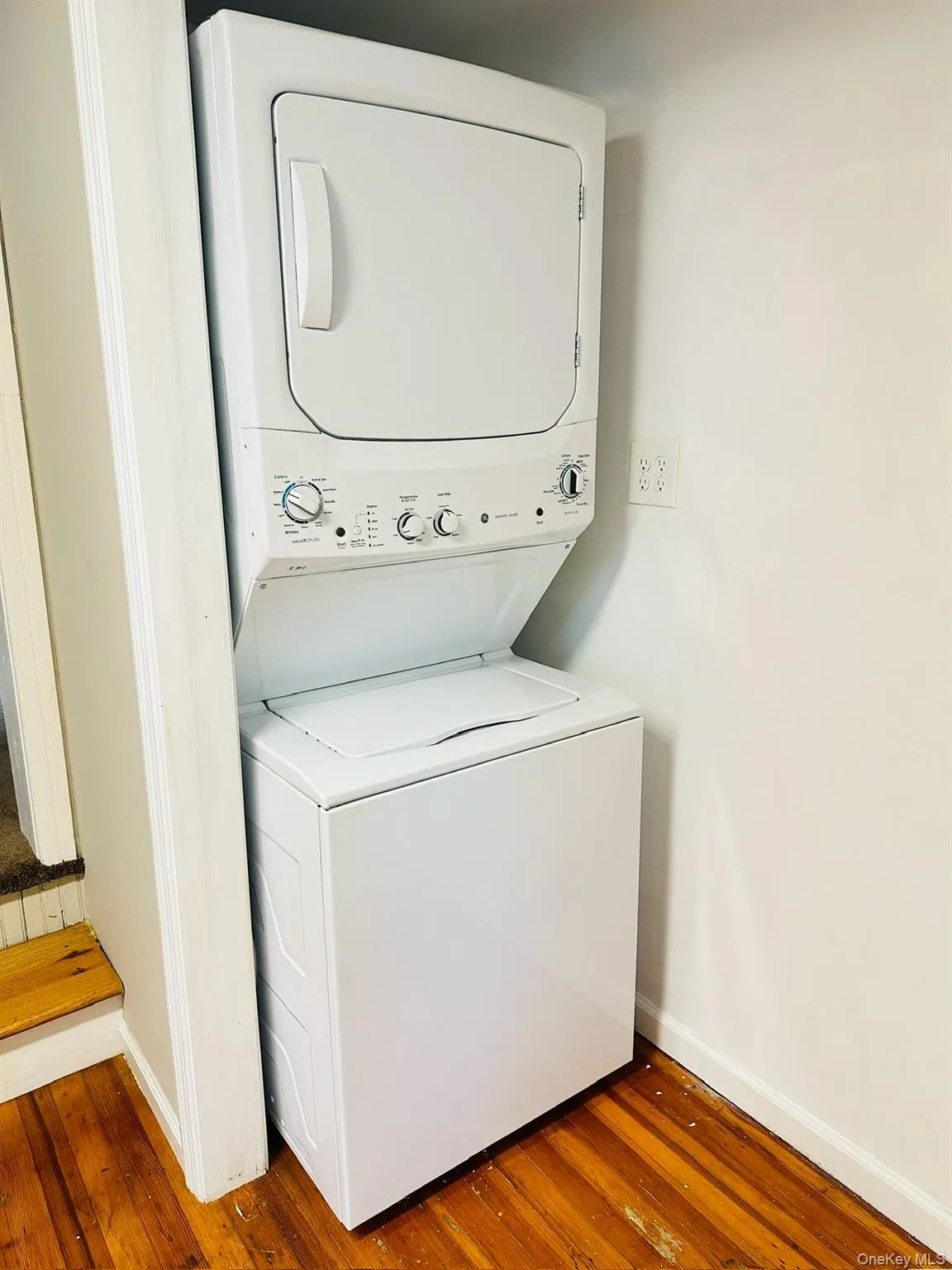 Laundry room with stacked washer / drying machine and hardwood / wood-style flooring Laundry room with stacked washer / drying machine and hardwood / wood-style flooring