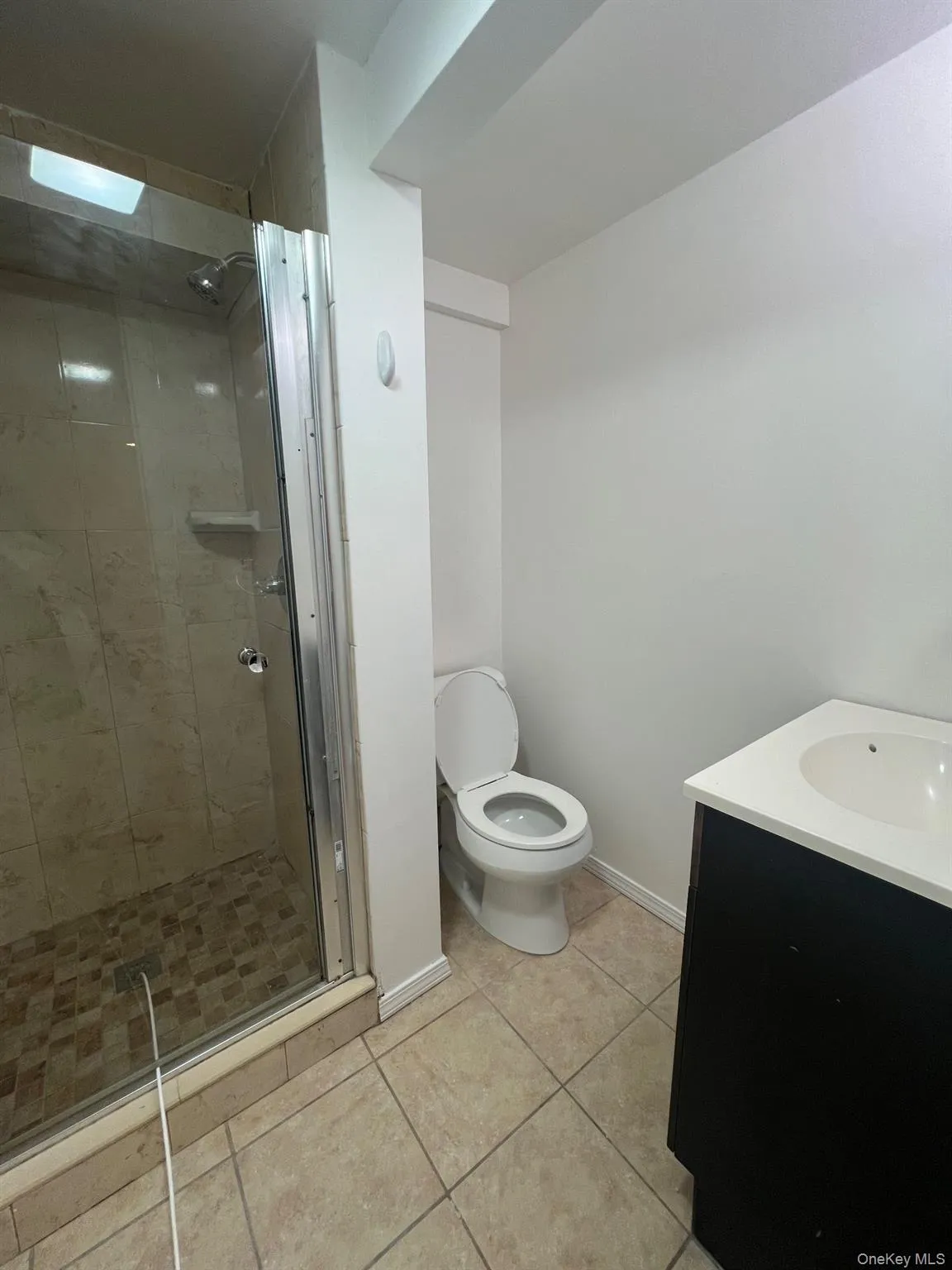 Full bath with vanity, a stall shower, and light tile patterned flooring Full bath with vanity, a stall shower, and light tile patterned flooring