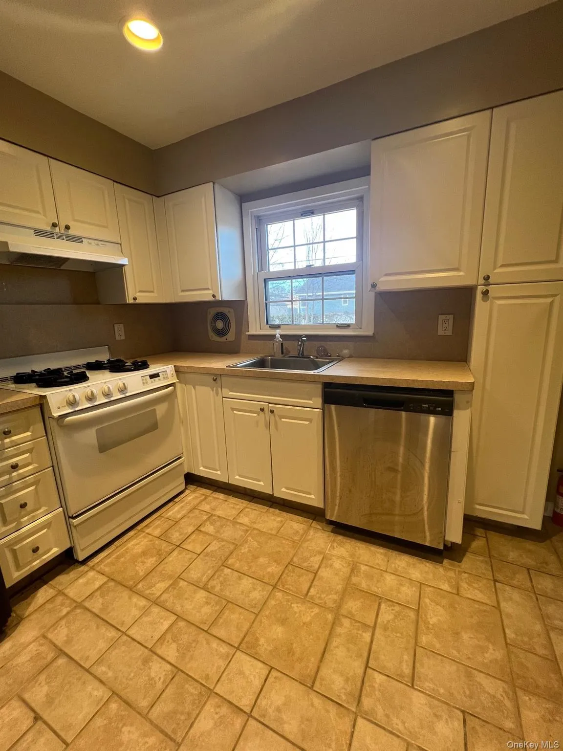 Kitchen with white gas range oven, white cabinetry, stainless steel dishwasher, light countertops, and recessed lighting Kitchen with white gas range oven, white cabinetry, stainless steel dishwasher, light countertops, and recessed lighting