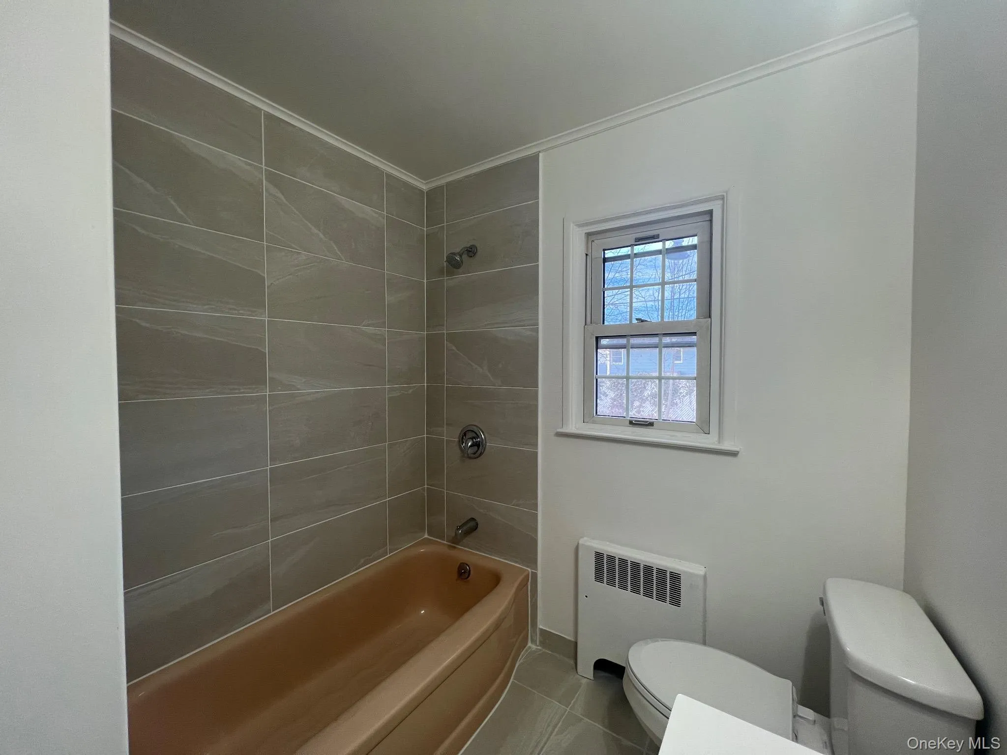 Bathroom with radiator, shower / bath combination, tile patterned flooring, and crown molding Bathroom with radiator, shower / bath combination, tile patterned flooring, and crown molding