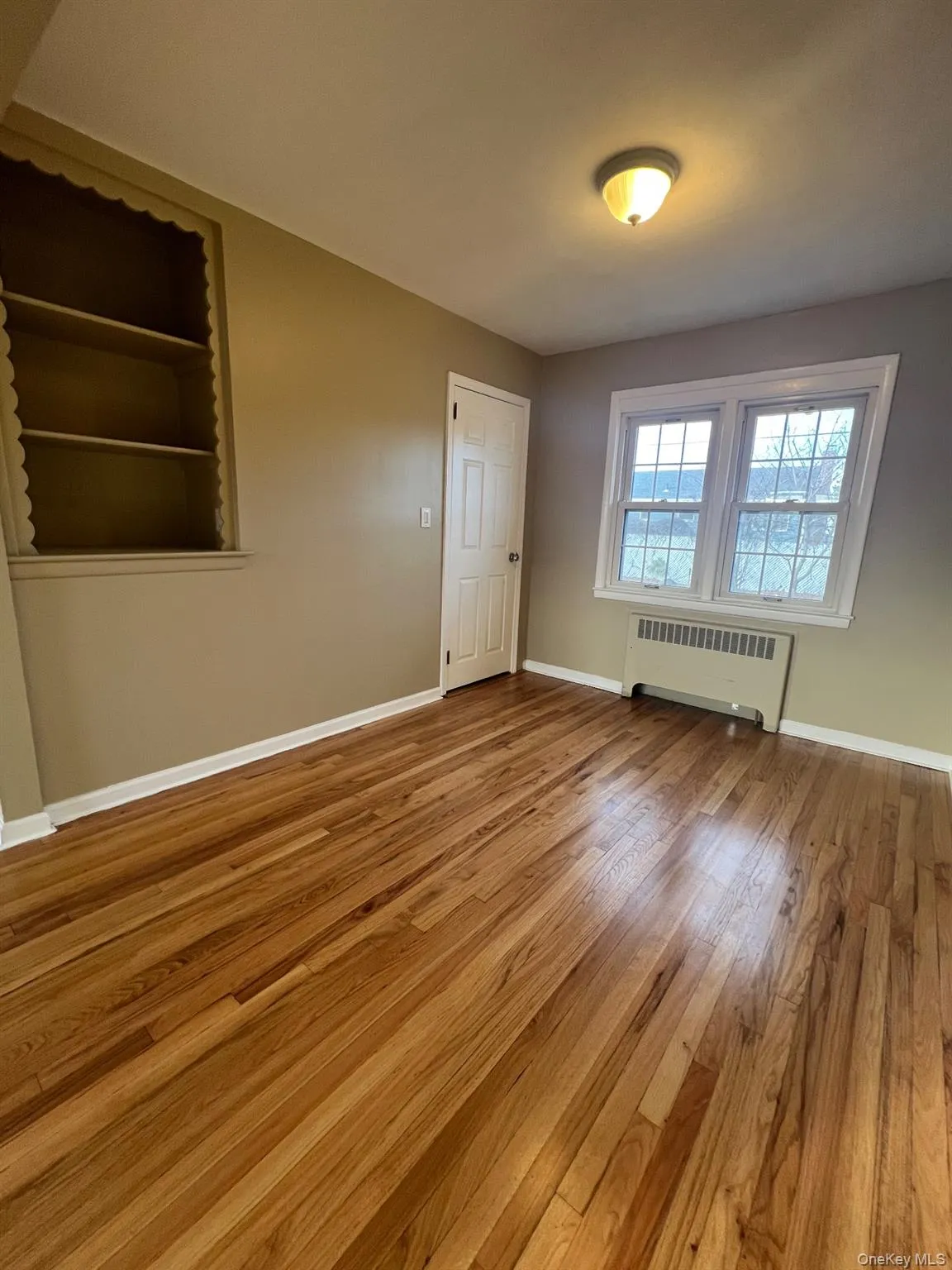 Unfurnished room with radiator and light wood-style floors Unfurnished room with radiator and light wood-style floors