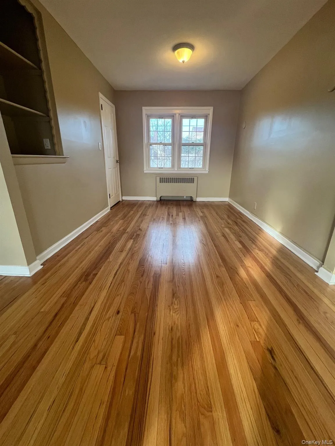 Empty room with light wood-style flooring and radiator Empty room with light wood-style flooring and radiator